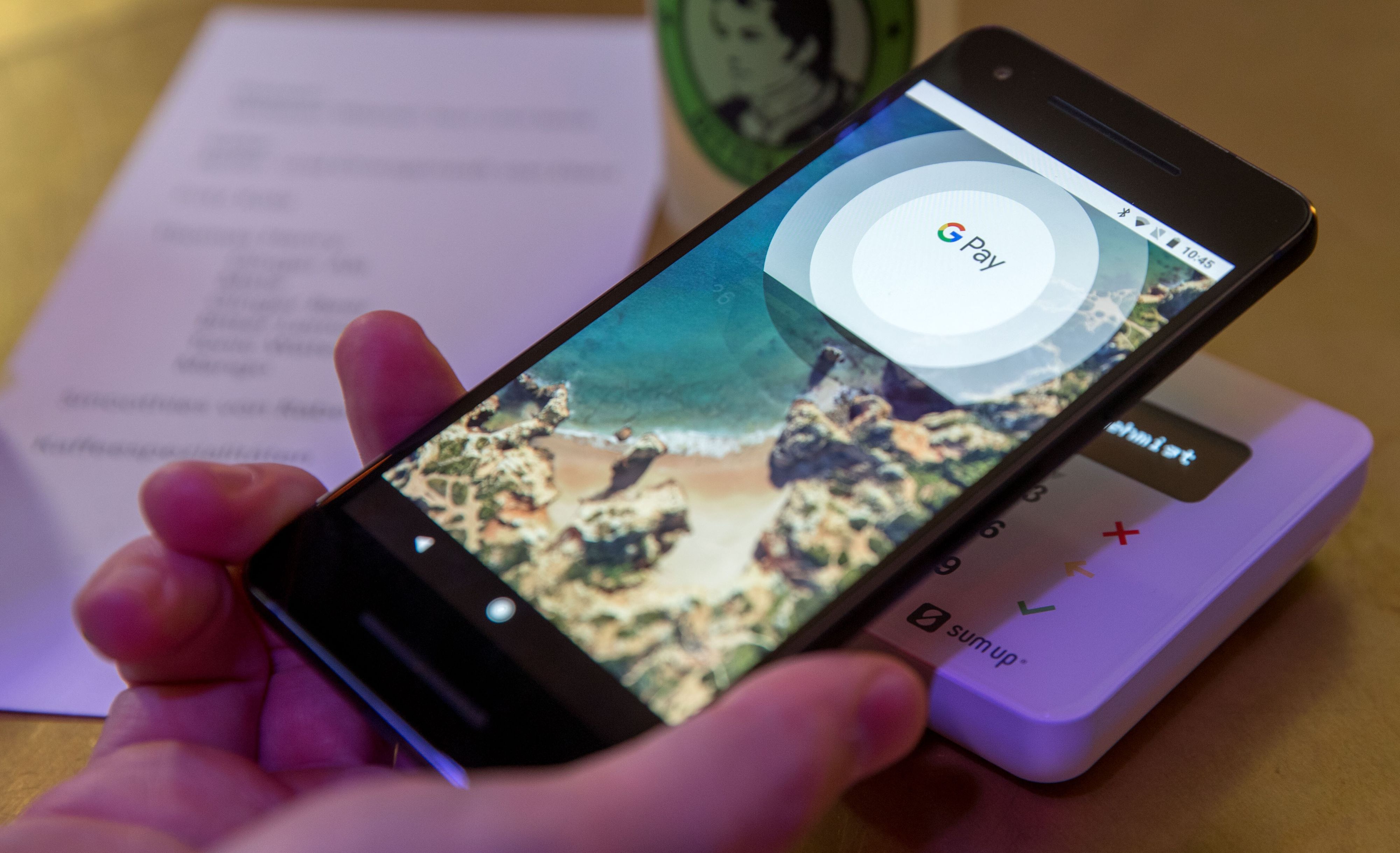 Ein Gast demonstriert mit einem Smartphone und der App des neuen Bezahldienstes Google Pay in einem Cafe das Bezahlen mit dem Handy.