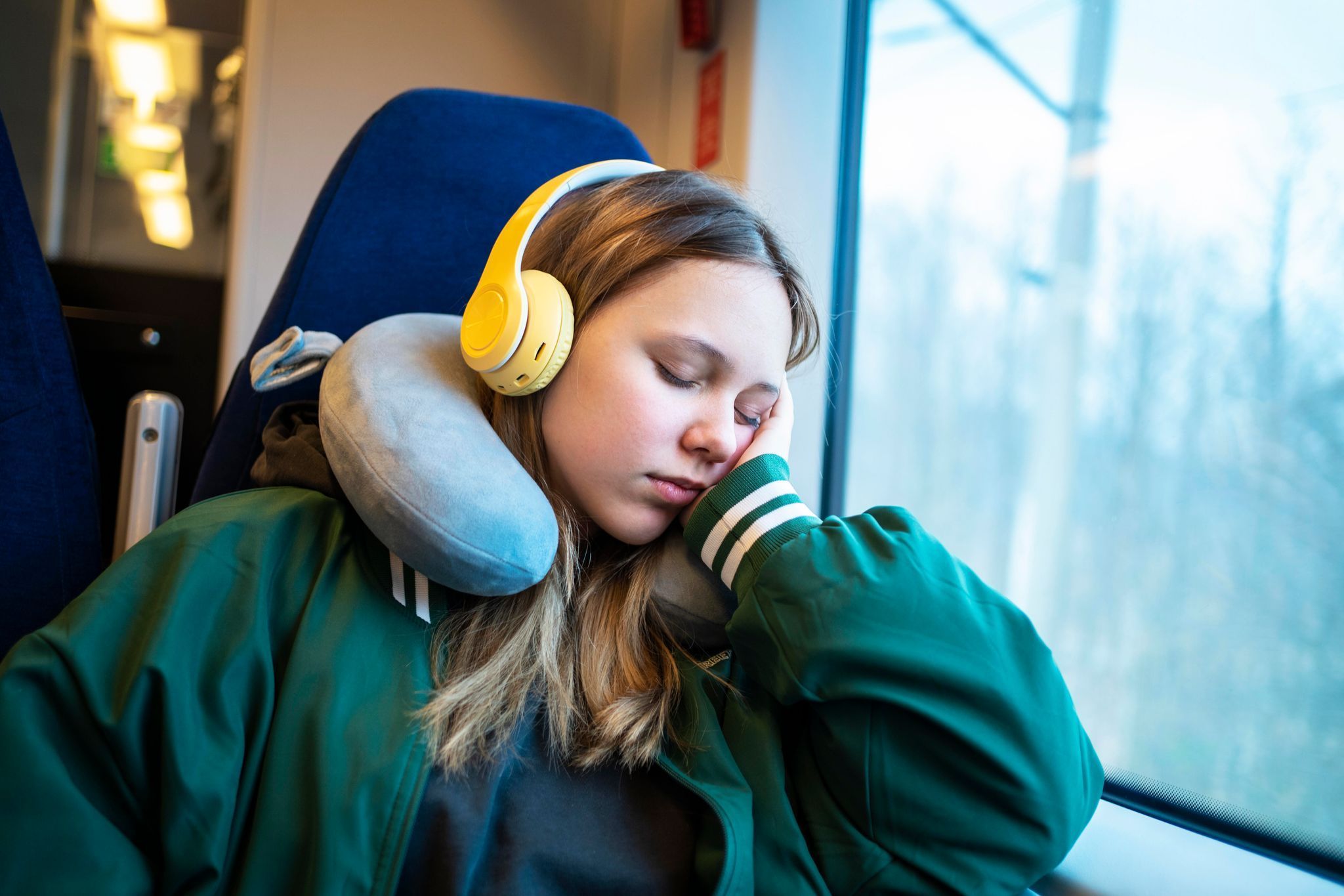 Mädchen schläft mit einem Nackenkissen im Zug