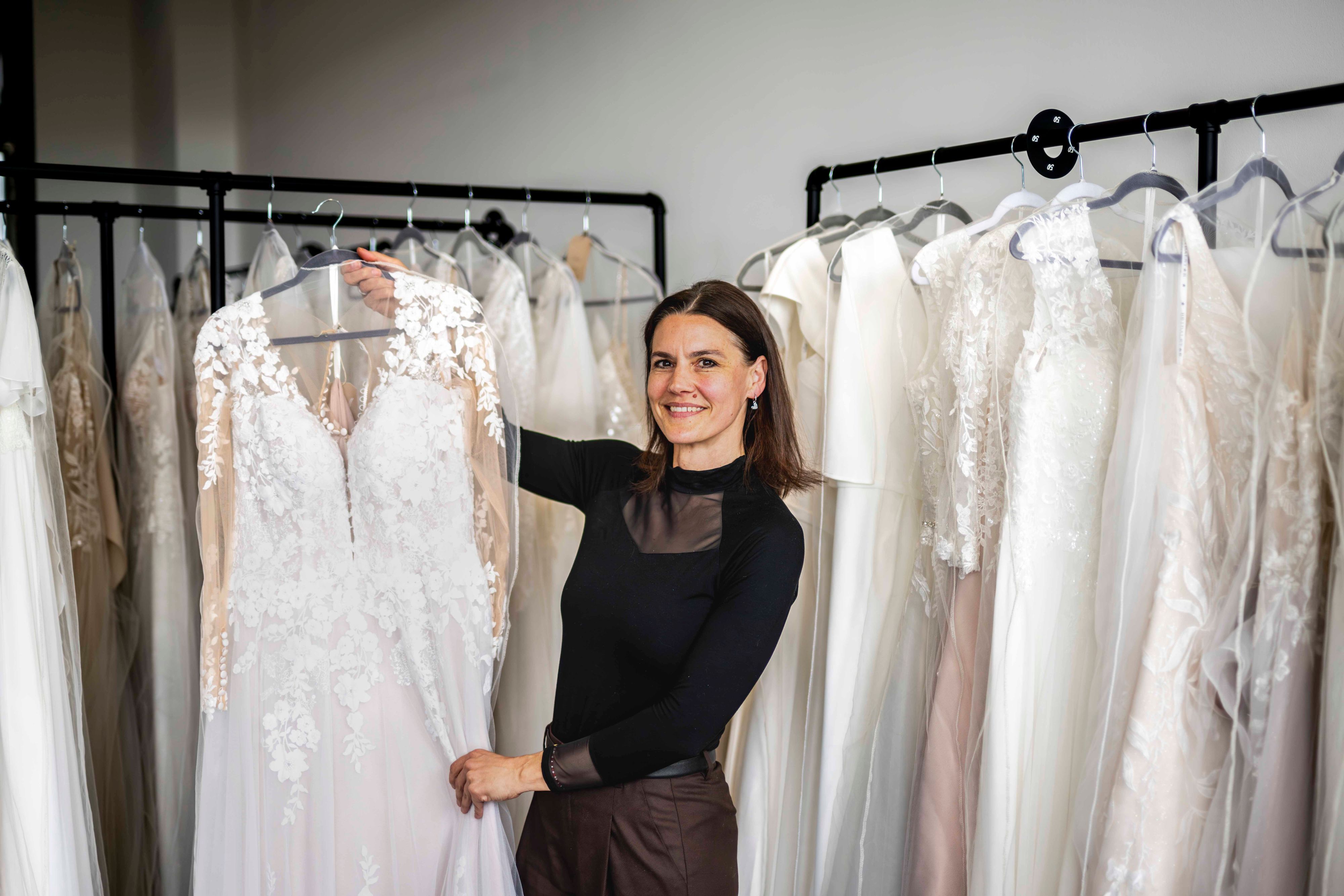 Das Bild zeigt Sina Heck, die ein Brautkleid in die Kamera hält.