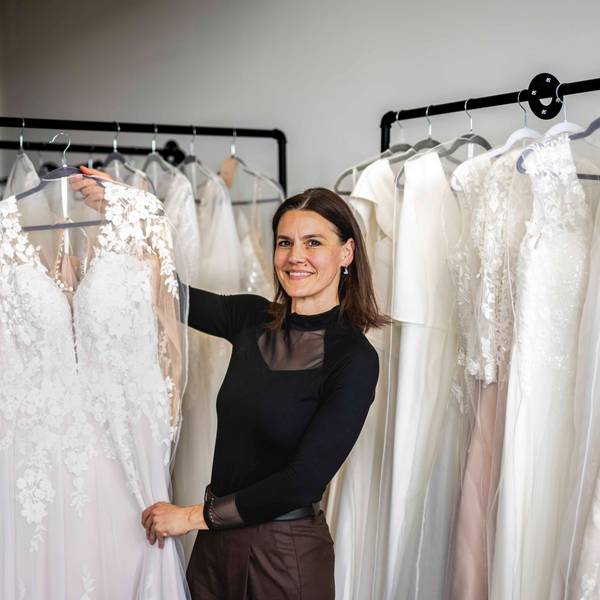Das Bild zeigt Sina Heck, die ein Brautkleid in die Kamera hält.
