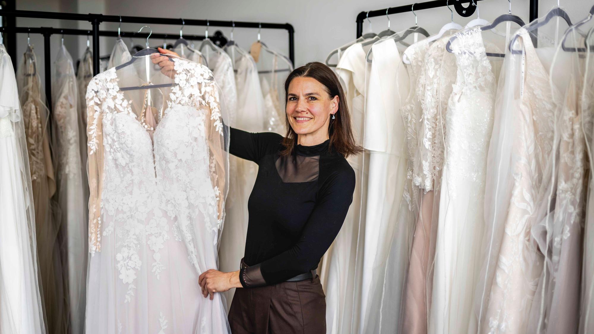 Das Bild zeigt Sina Heck, die ein Brautkleid in die Kamera hält.