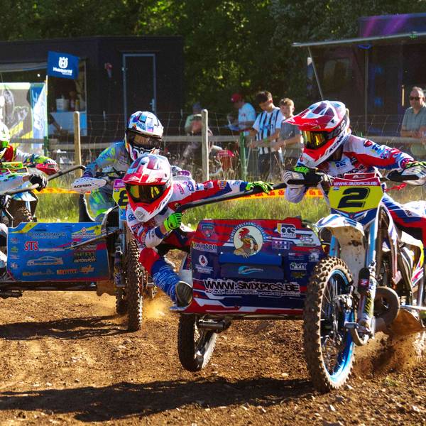 Drei Motocross-Maschinen mit Seitenwagen fahren durch eine Kurve, die Beifahrer hängen artistisch am Seitenwagen.