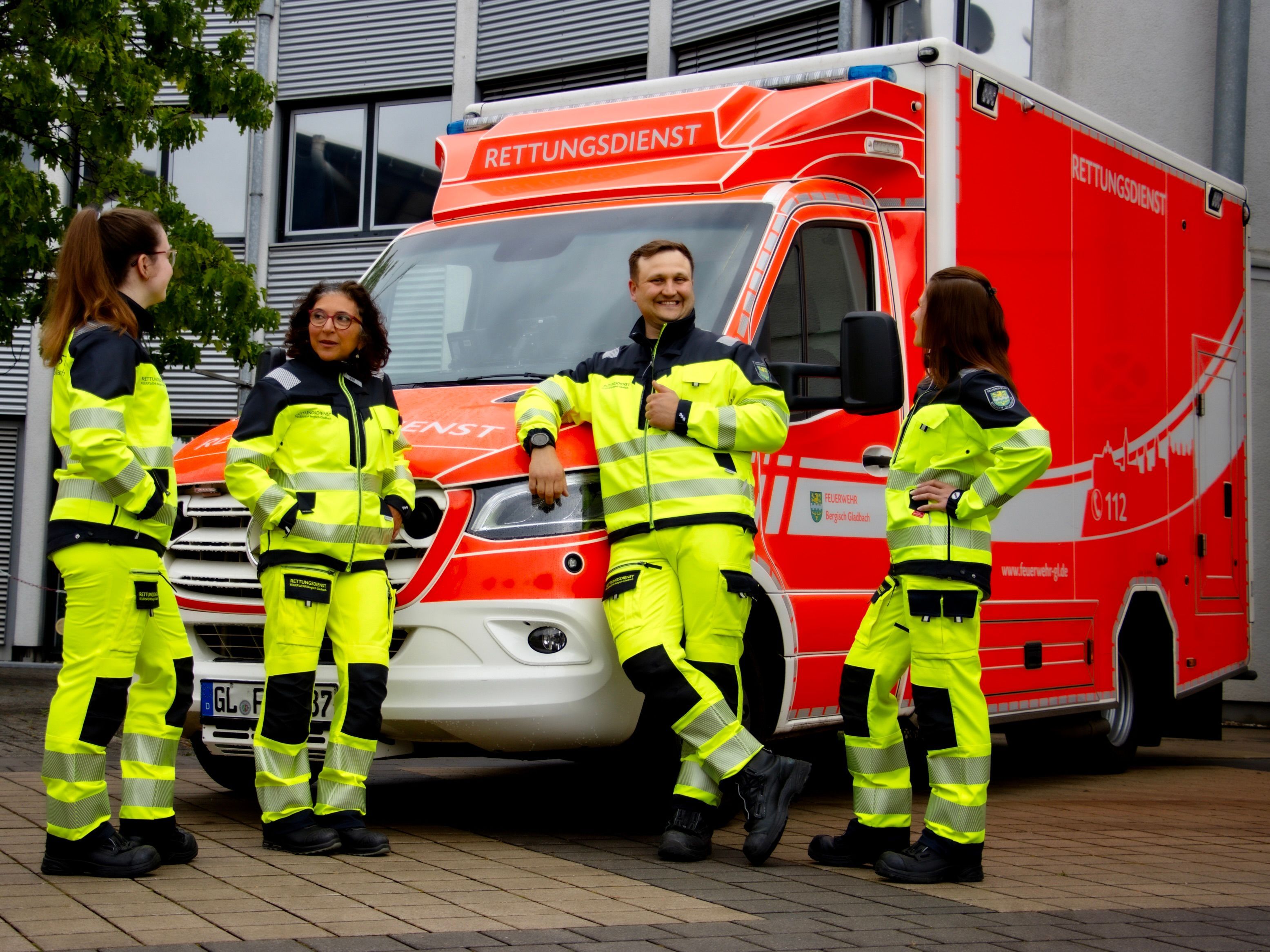 Rettungsdienstmitarbeitende stehen vor einem Rettungswagen der Feuerwehr Bergisch Gladbach.