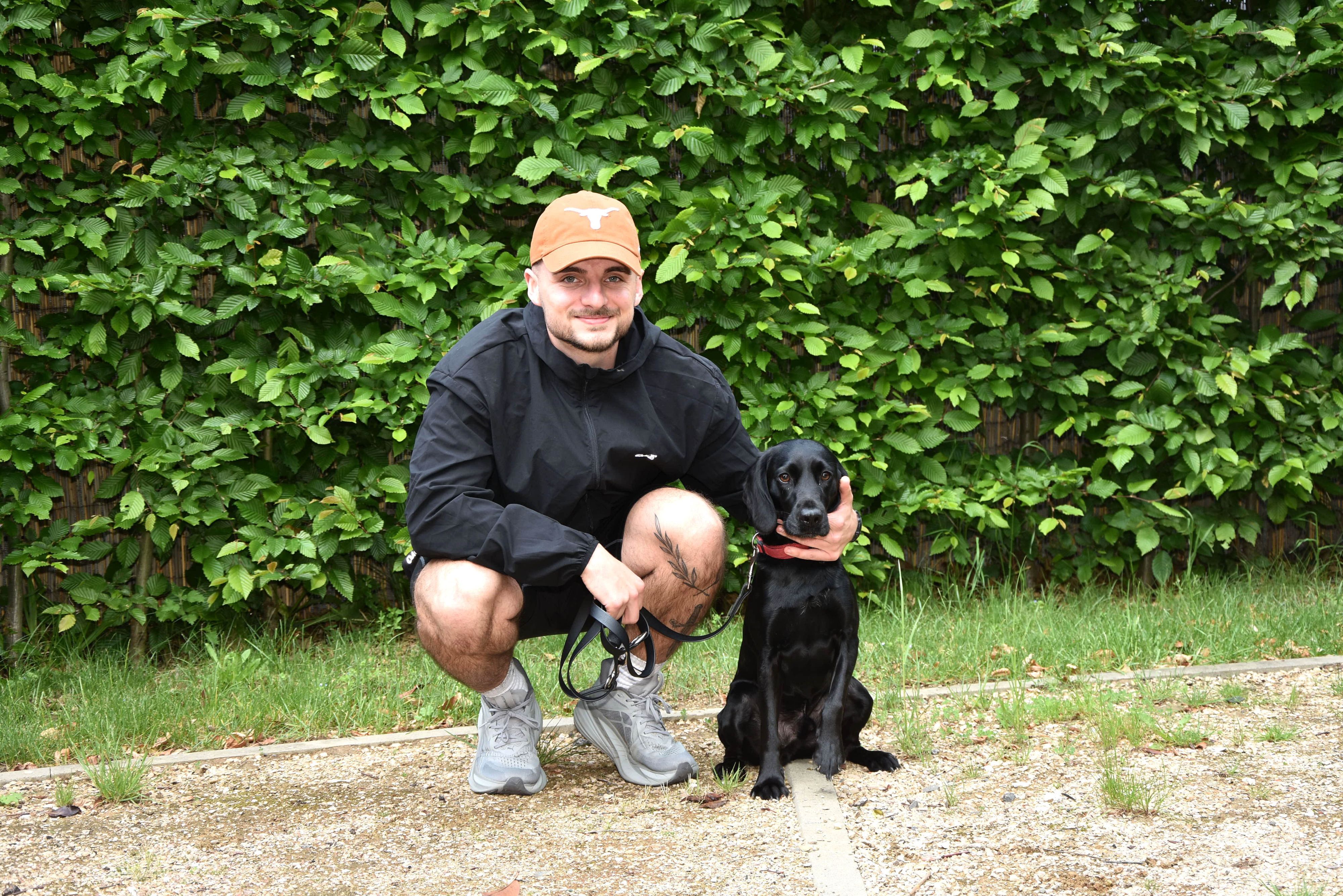 Das Foto zeigt einen Mann mit einem schwarzen Hund.