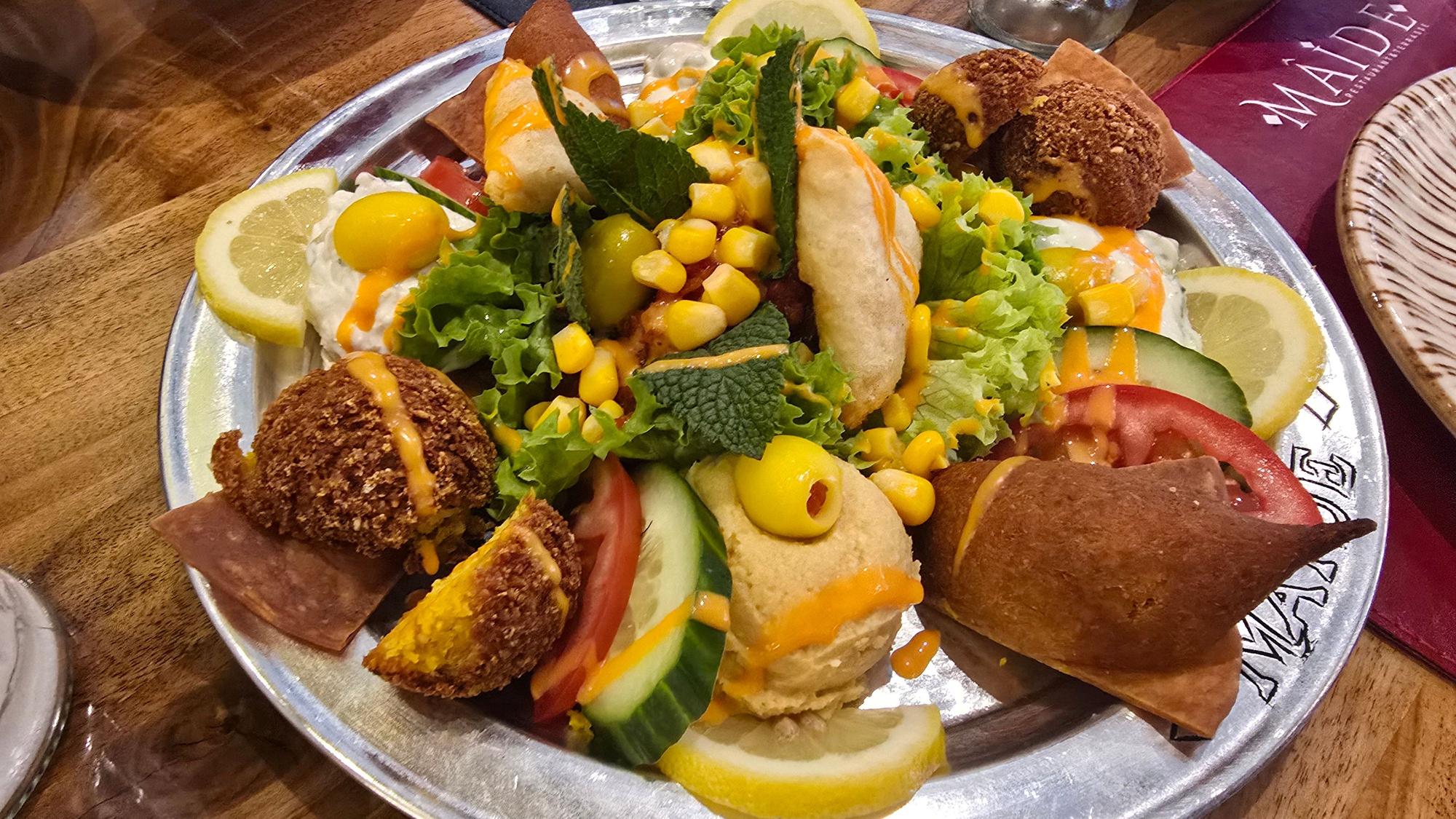 Die gemischte Vorspeisenplatte mit unterschiedlichen Dips und Falafel auf einem Teller mit Zitronenscheiben garniert.