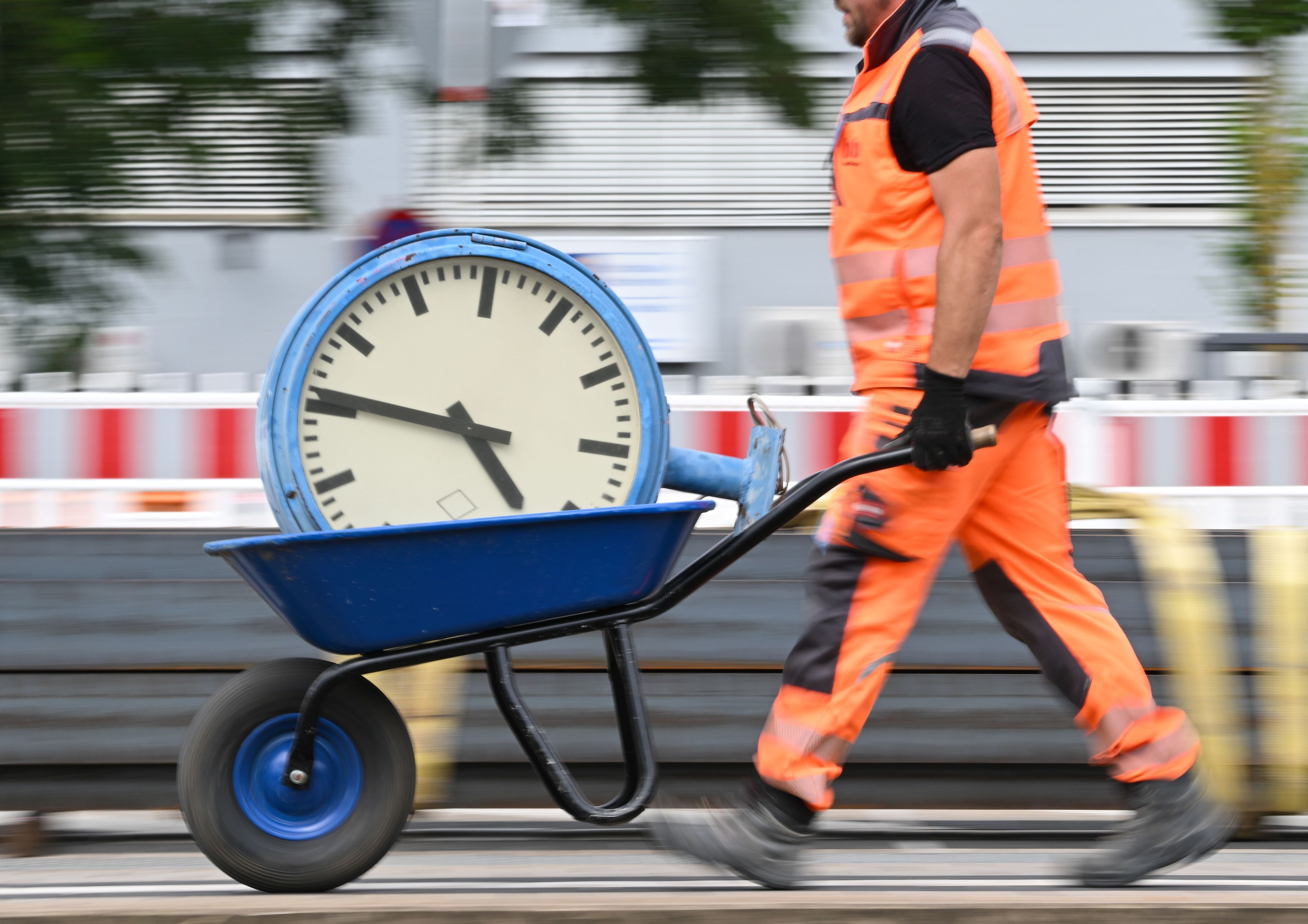 ARCHIV - 17.07.2024, Hessen, Mörfelden-Walldorf: Ein Arbeiter transportiert eine Bahnhofsuhr auf einer Schubkarre. (zu dpa: «Niedersachsen arbeiten 2025 drei Stunden weniger») Foto: Arne Dedert/dpa +++ dpa-Bildfunk +++