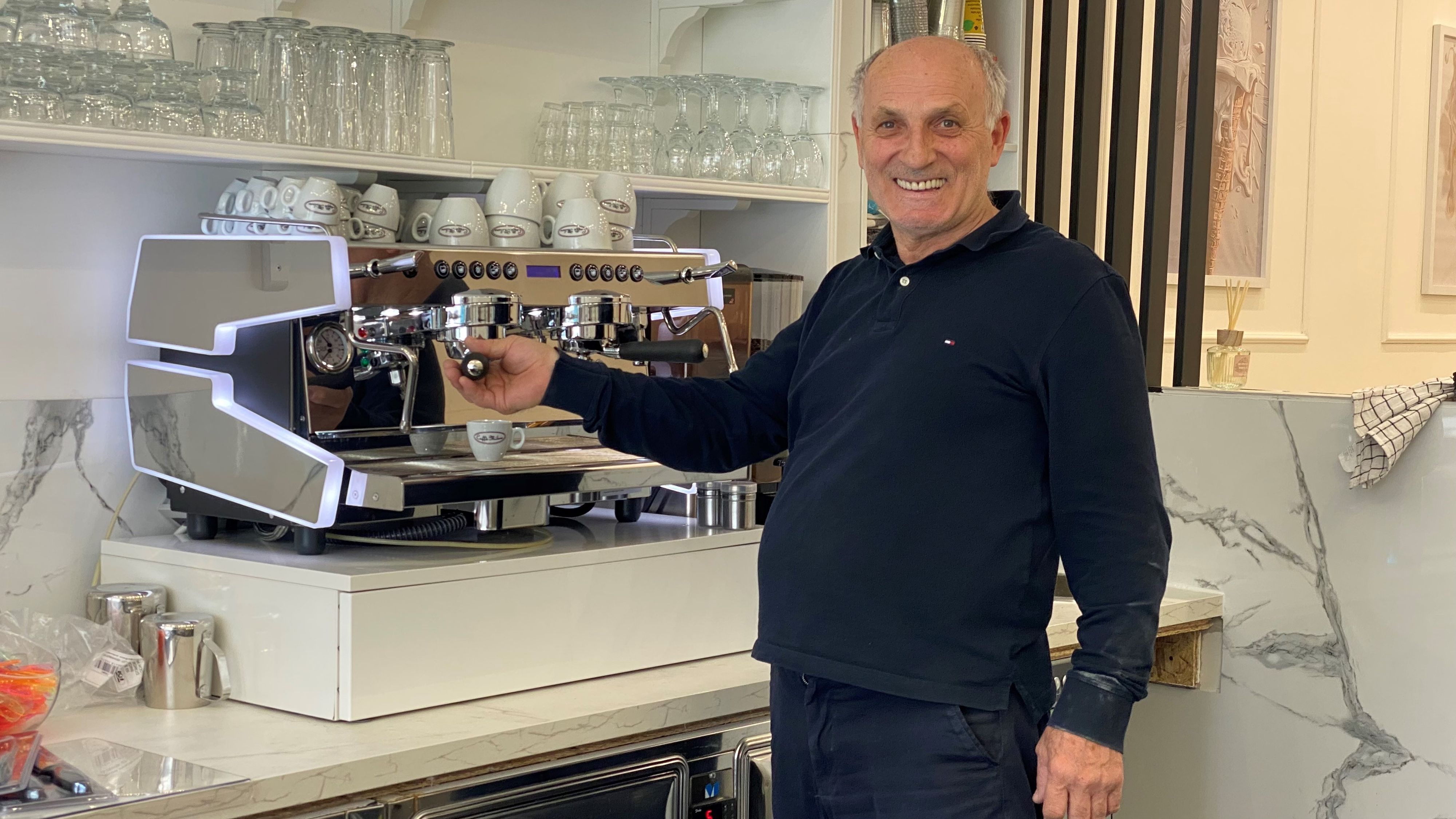 Zu sehen ist ein Mann an einer großen Kaffeemaschine.