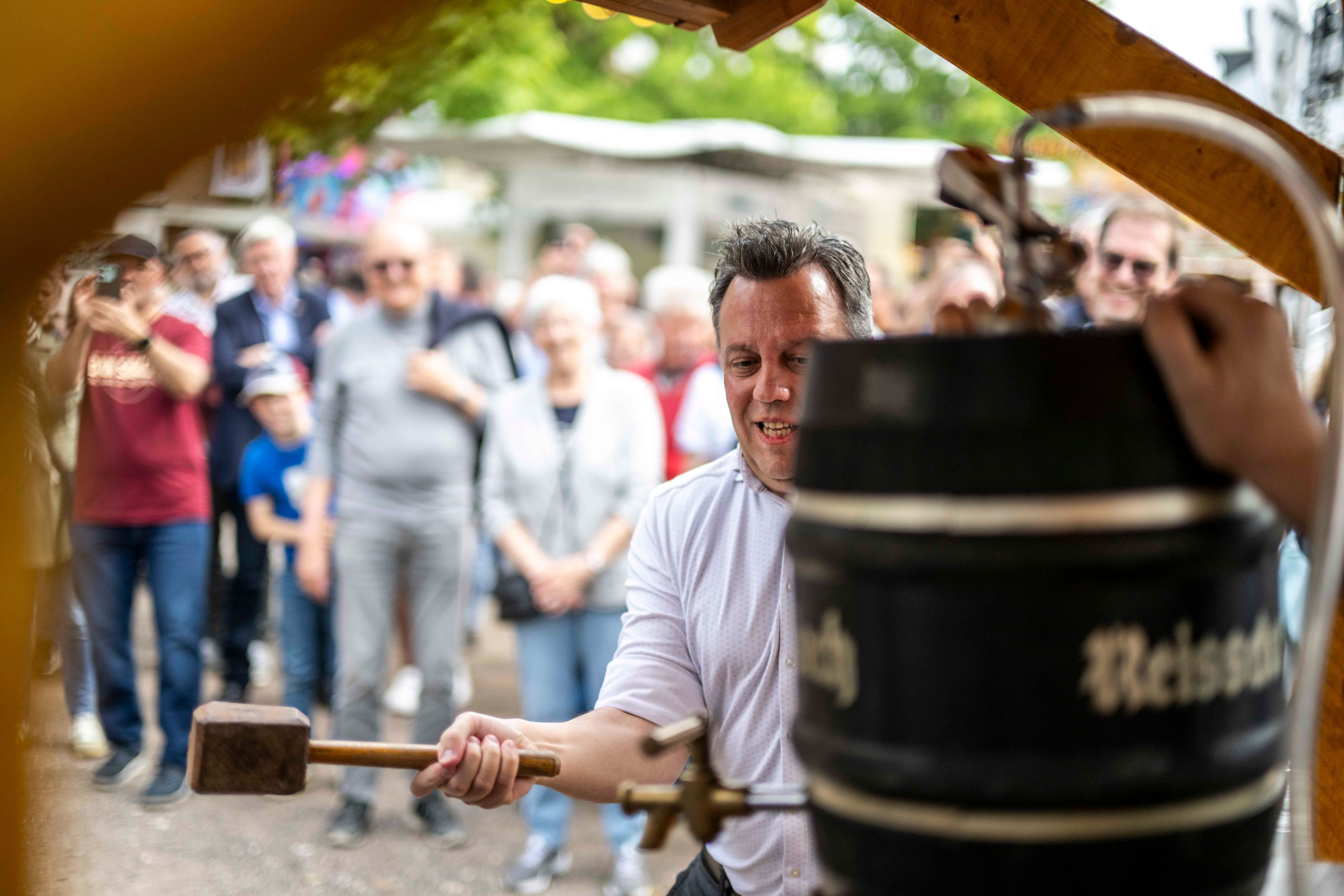Das Bild zeigt den Verwaltungschef mit einem Holzhammer in der Hand, wie er auf ein Bierfass einschlägt.