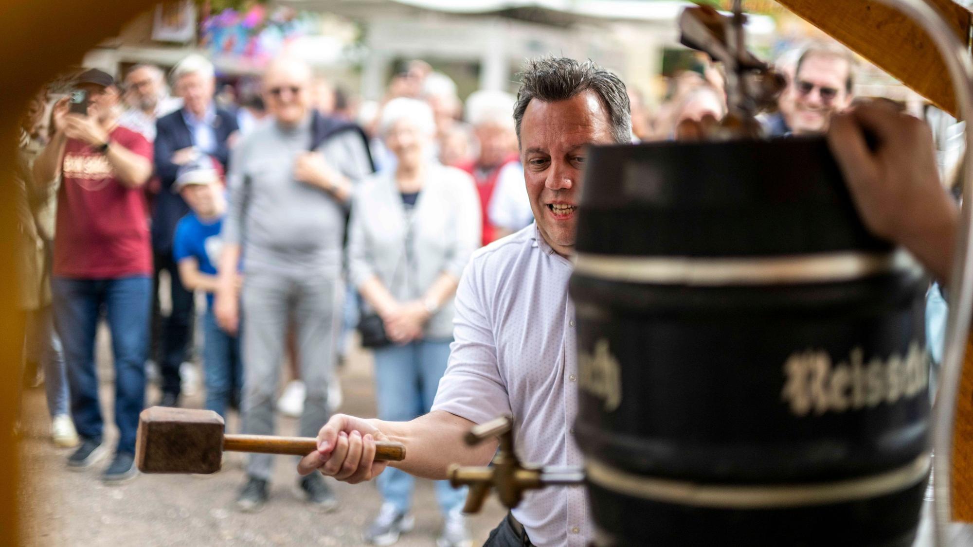 Das Bild zeigt den Verwaltungschef mit einem Holzhammer in der Hand, wie er auf ein Bierfass einschlägt.