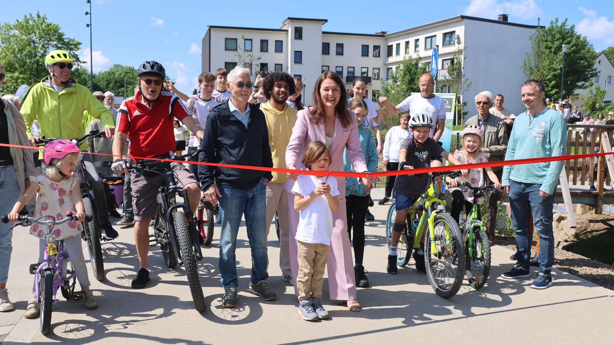 Larissa Weber und Vincent Gülmen zerschneiden das rote Band und geben den City-Radweg frei.