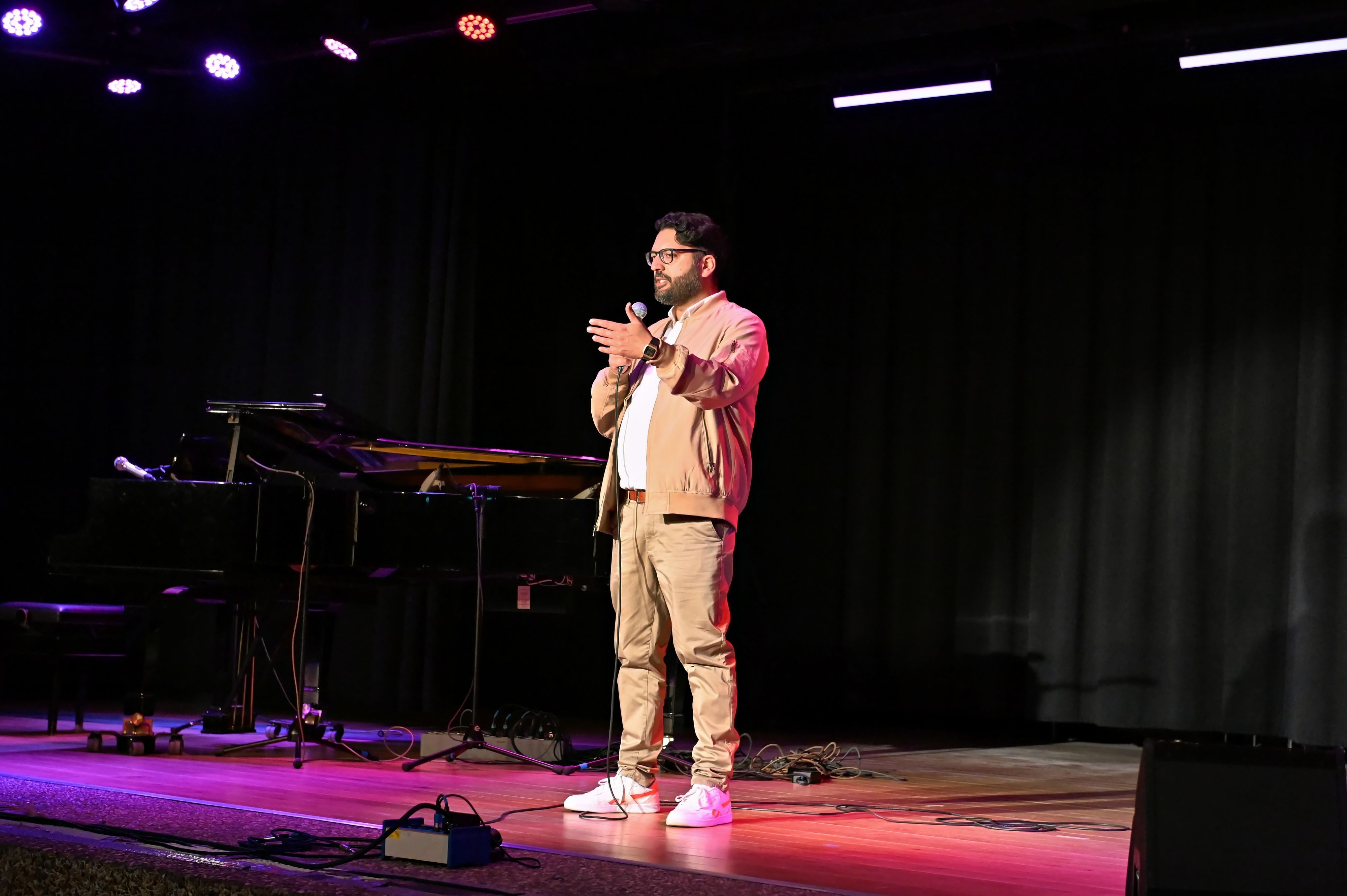 Amir Shahbazz bei seinem Auftritt in Euskirchen. Er trägt Vollbart, eine Brille sowie eine beige Hose und ein weißes Hemd unter einer beigen Jacke.