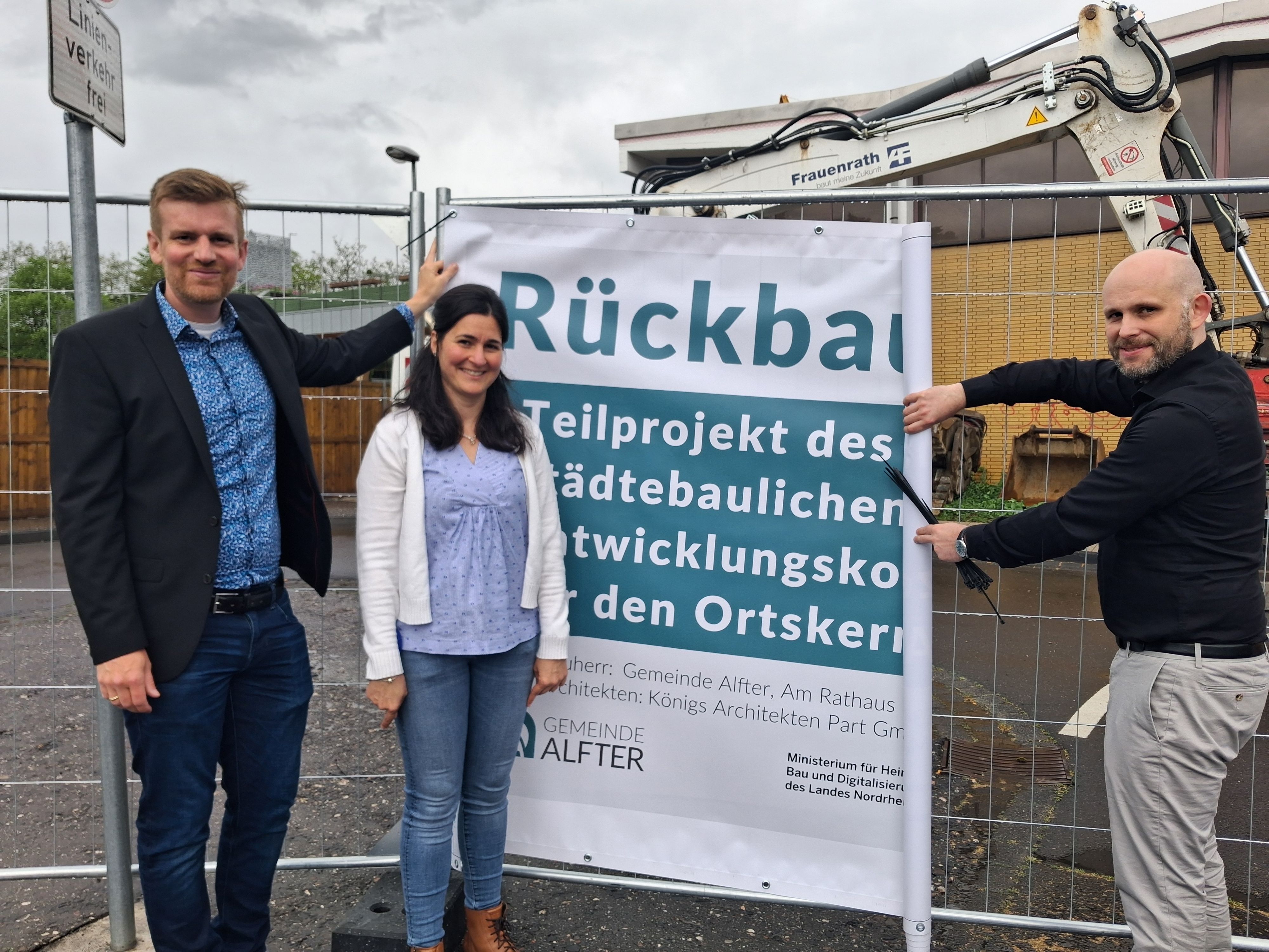 Christian Lanzrath, Olivia Dominick und Oliver Ernst (von links) mit dem Banner am Bauzaun.