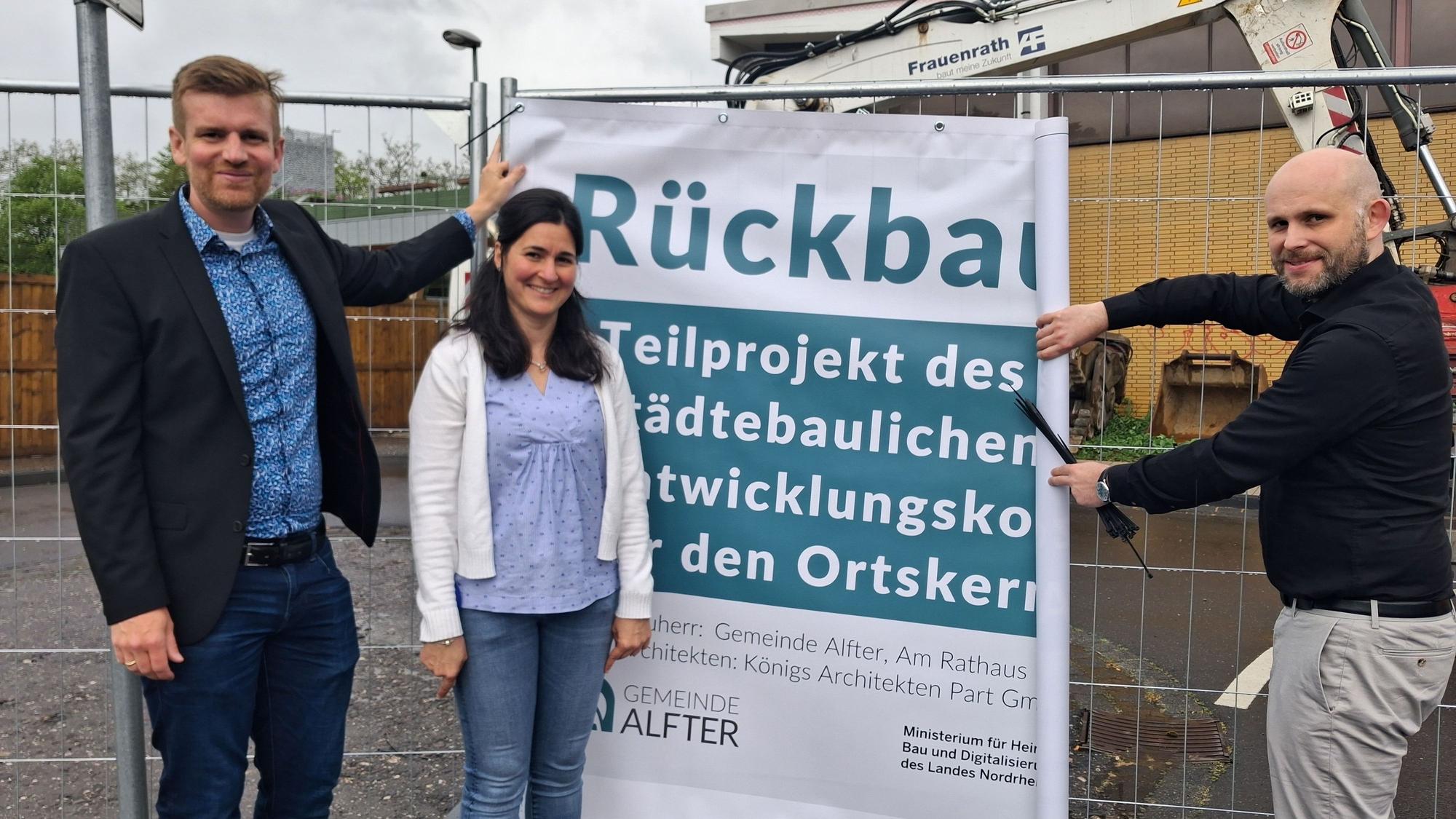 Christian Lanzrath, Olivia Dominick und Oliver Ernst (von links) mit dem Banner am Bauzaun.
