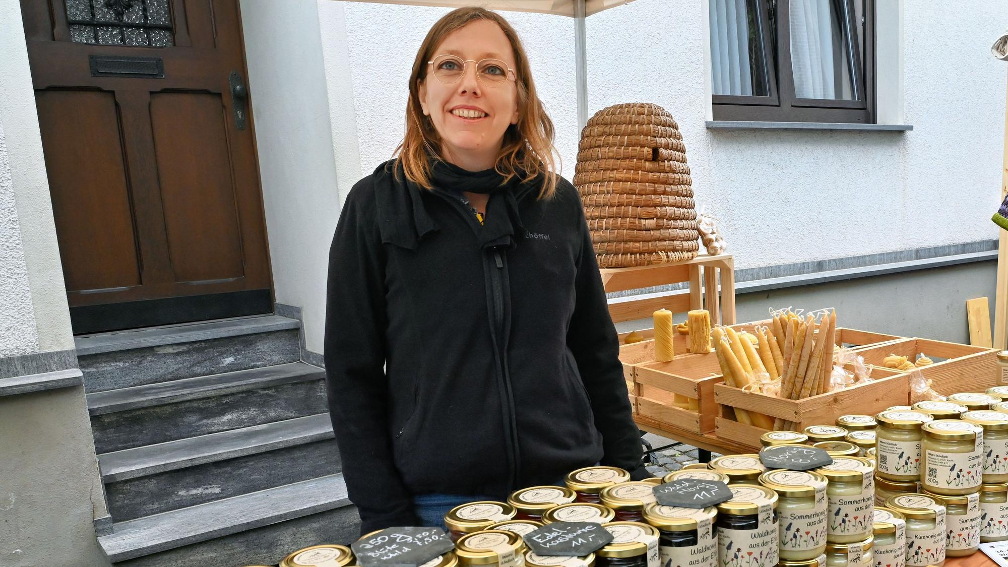 Eine Frau steht hinter einer Reihe gestapelter Honiggläser.