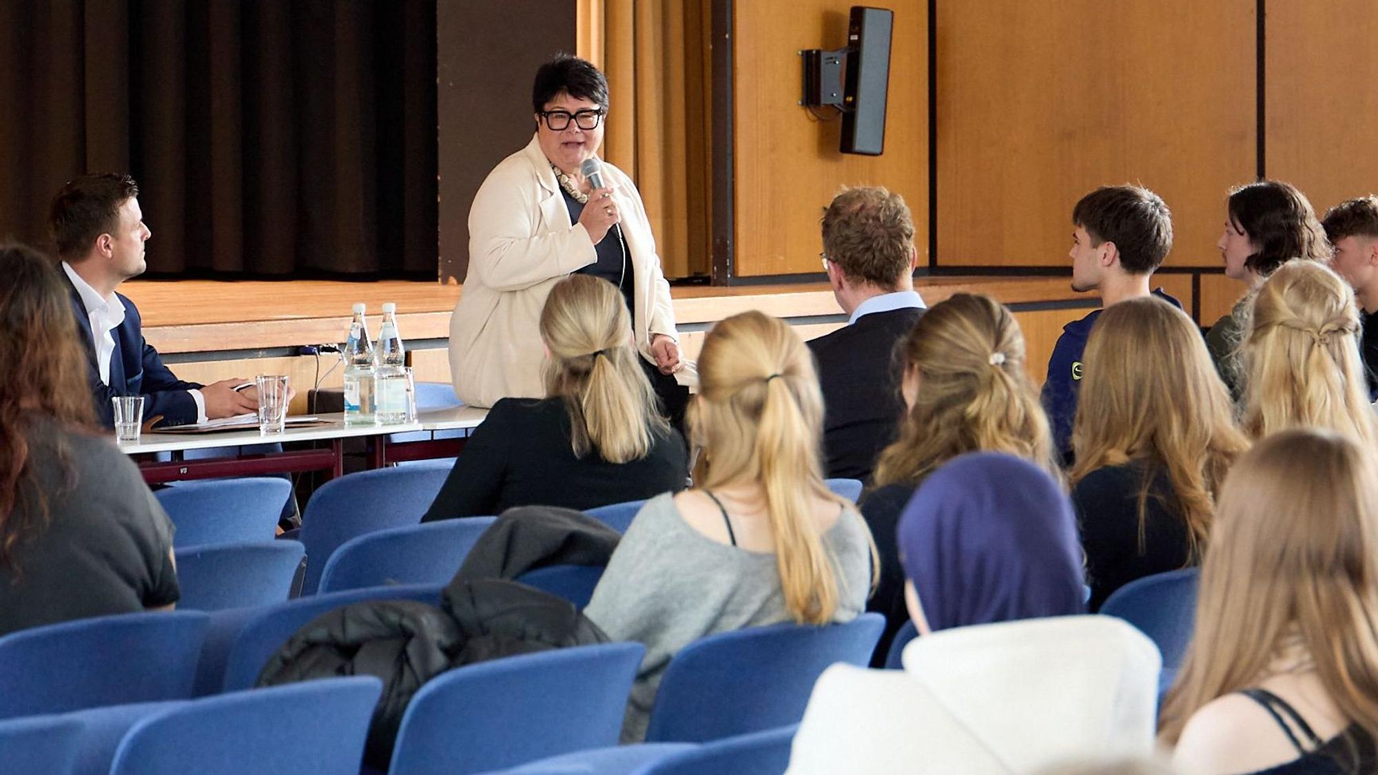 Sabine Verheyen spricht vor den zuhörenden Schülern in der Aula in ein Mikrofon.