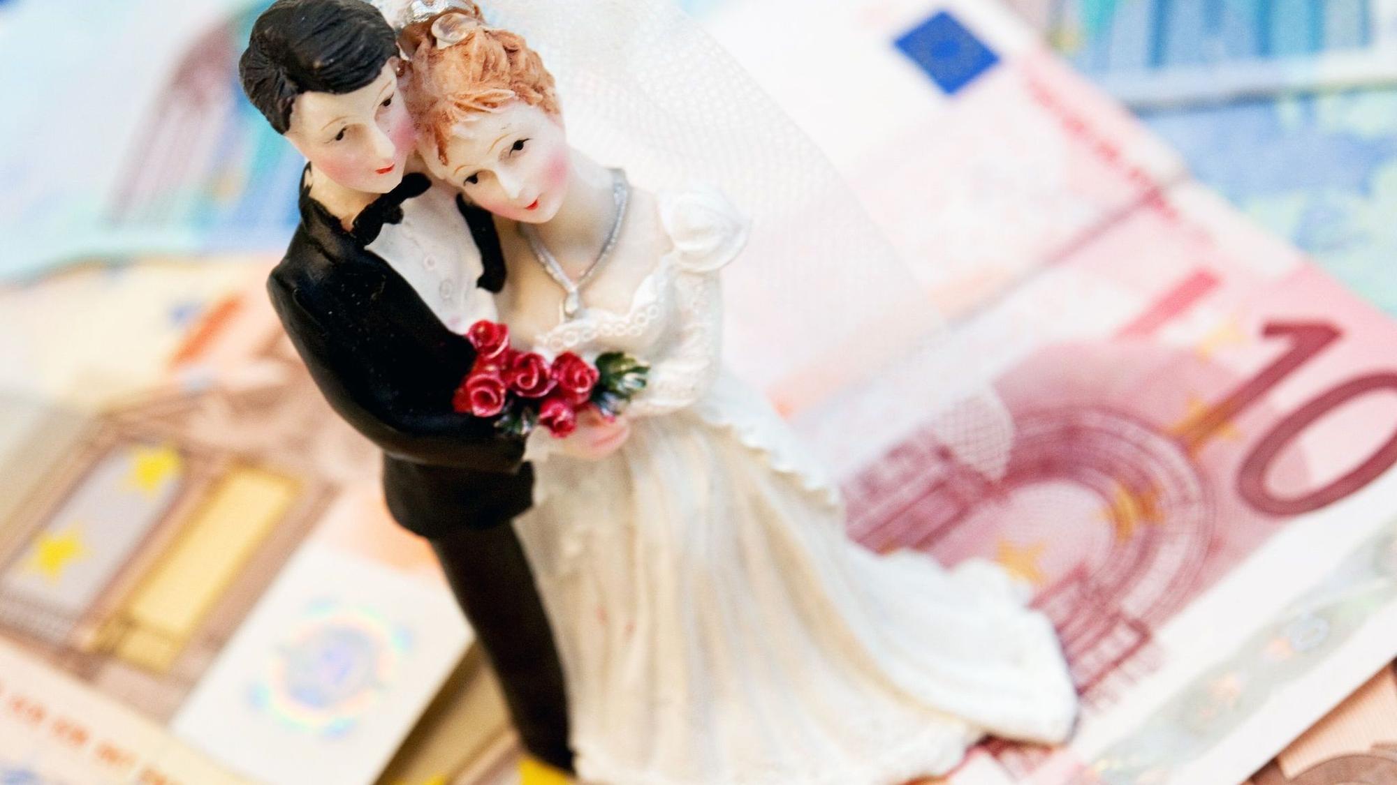Eine Brautpaarfigurine steht auf Geldscheinen
