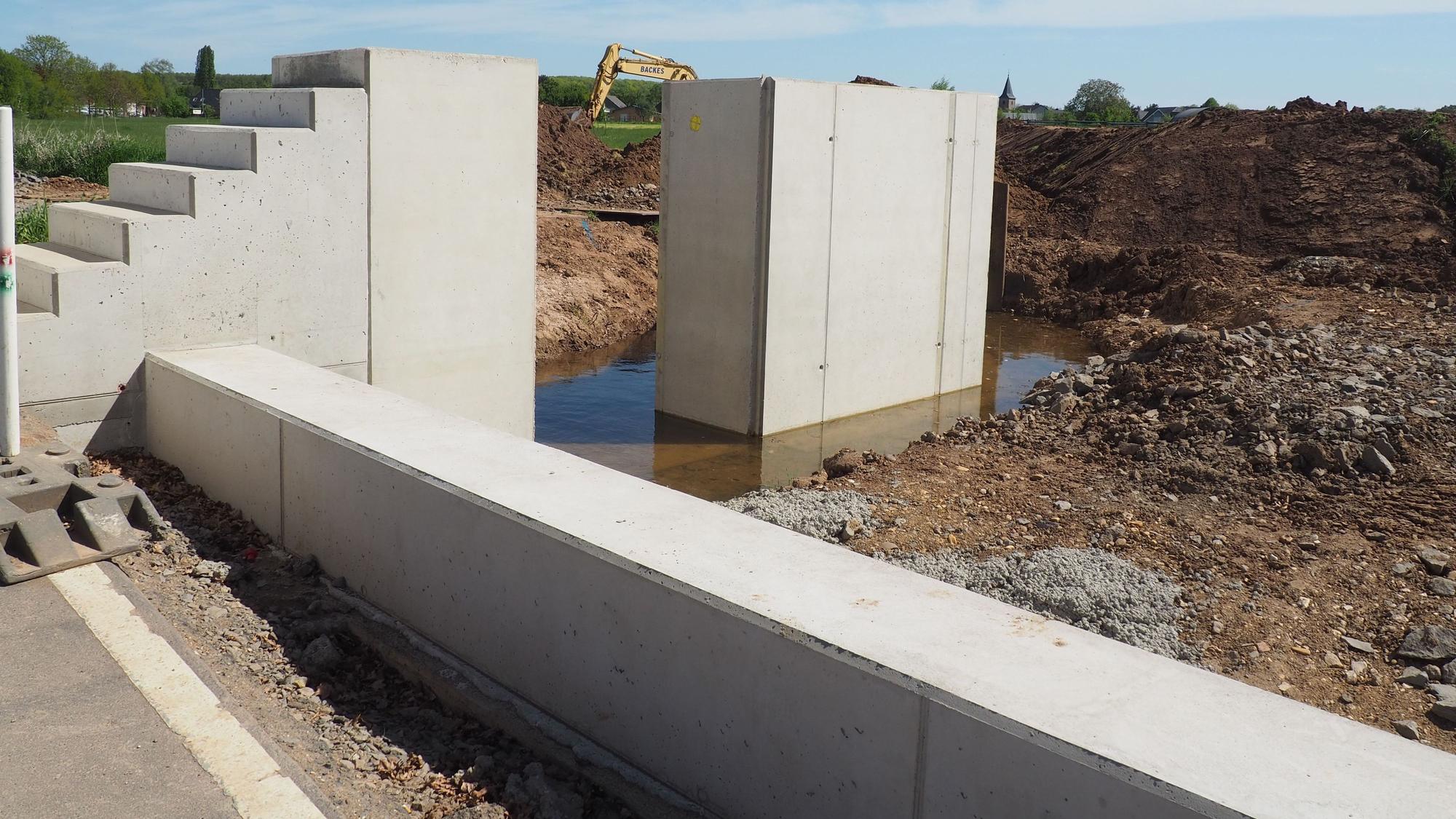 Im Vordergrund verläuft die Schwelle, hinter der später der Vlattener Bach fließen wird. Eine Betontreppe führt aufwärts bis zu einer Lücke zwischen zwei Betonelementen.