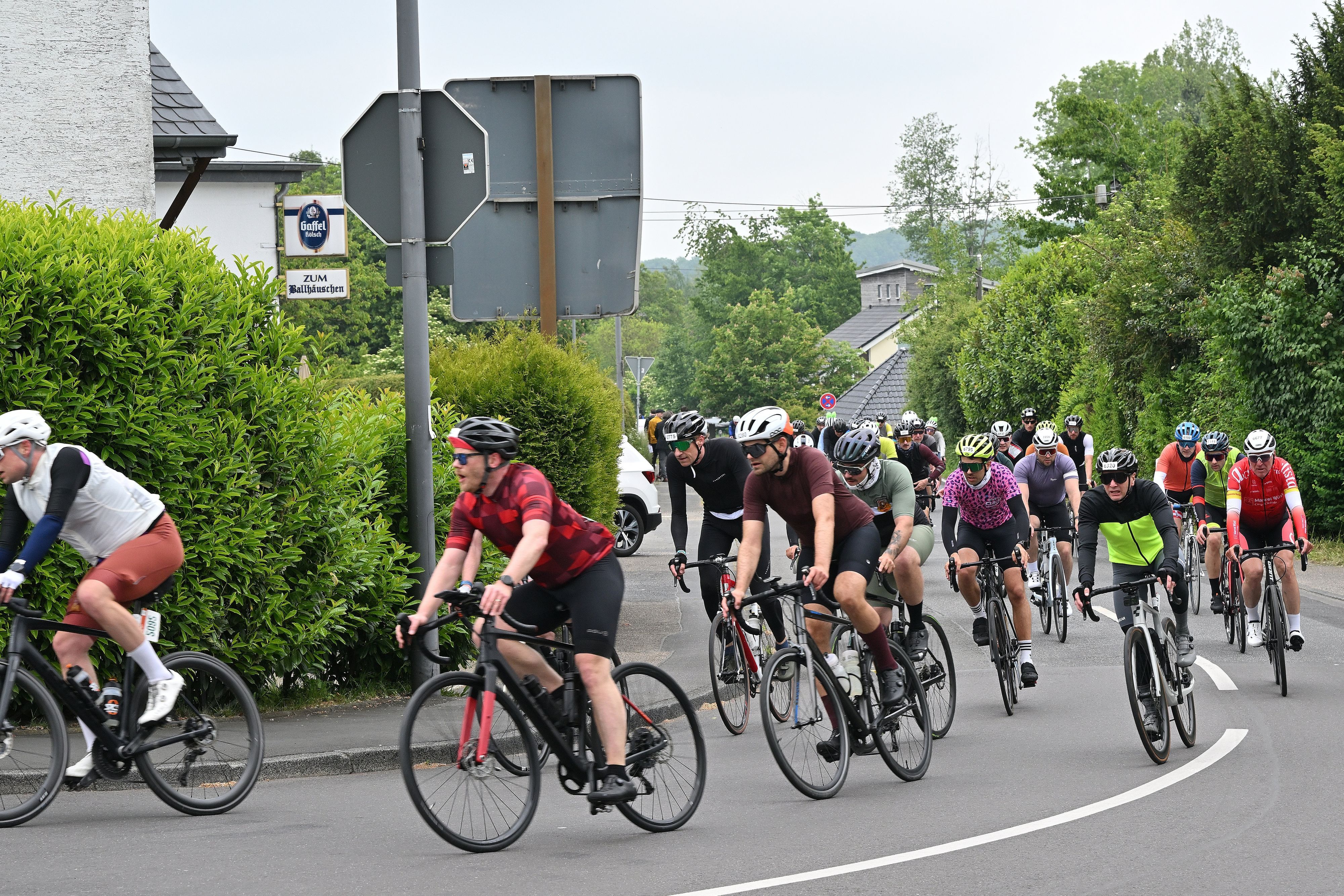 Zu sehen ist eine große Gruppe Radfahrer, die um eine Kurve biegt.