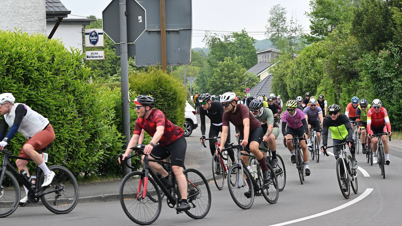 Zu sehen ist eine große Gruppe Radfahrer, die um eine Kurve biegt.