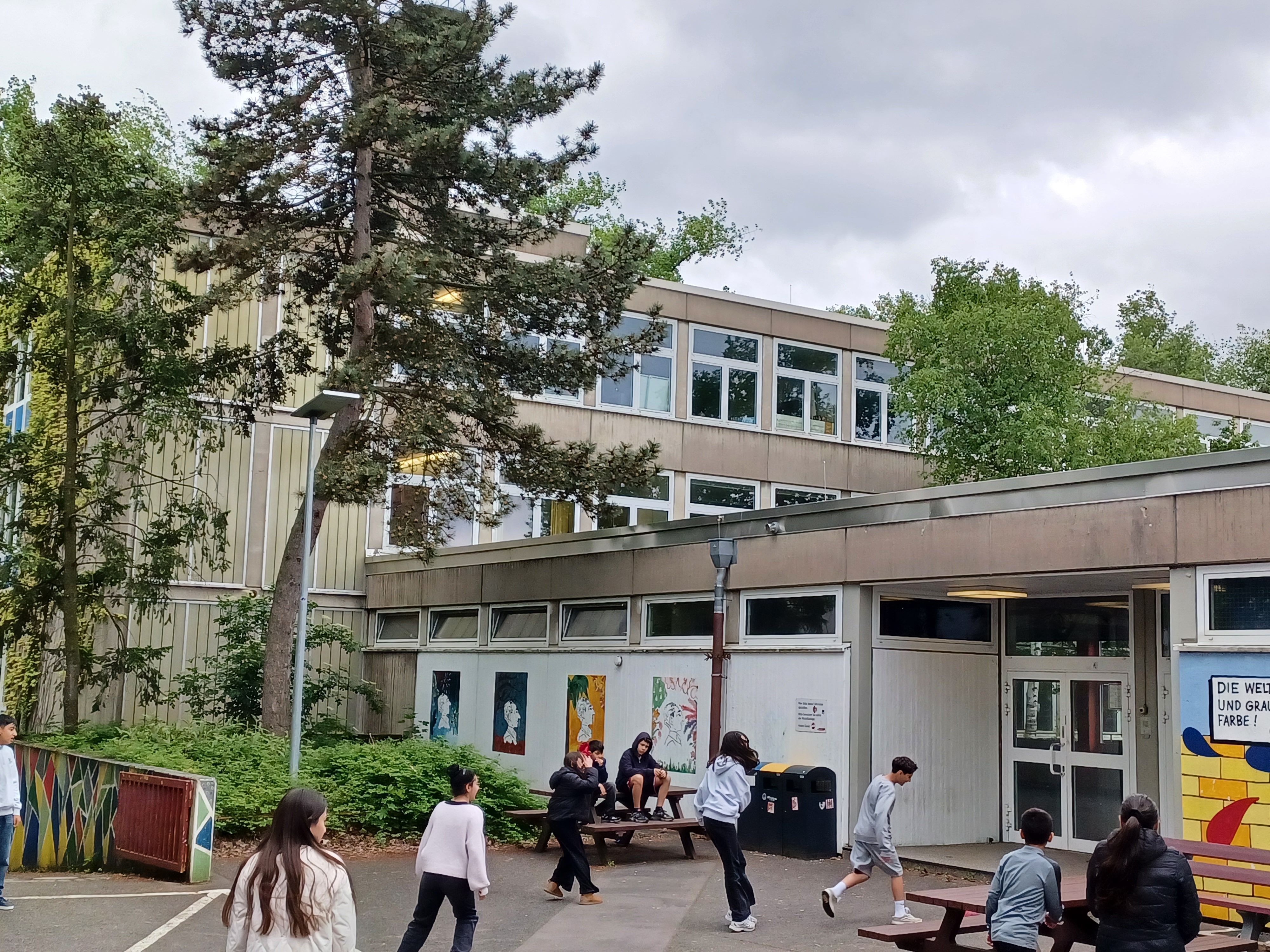 Blick auf den Eingang des Erich-Kästner-Gymnasiums, vor dem sich Schülerinnen und Schüler aufhalten.