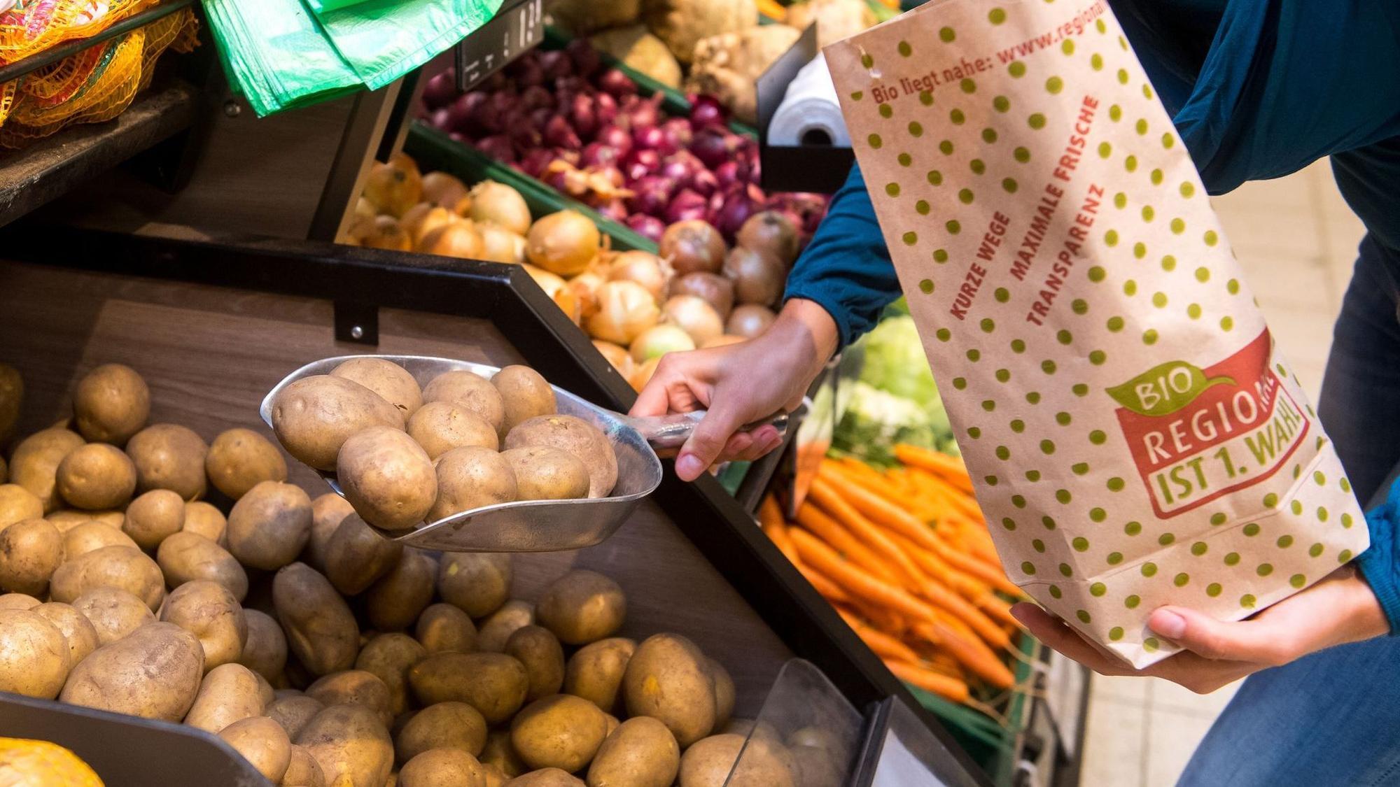 Eine Frau füllt Kartoffeln in eine Papiertüte