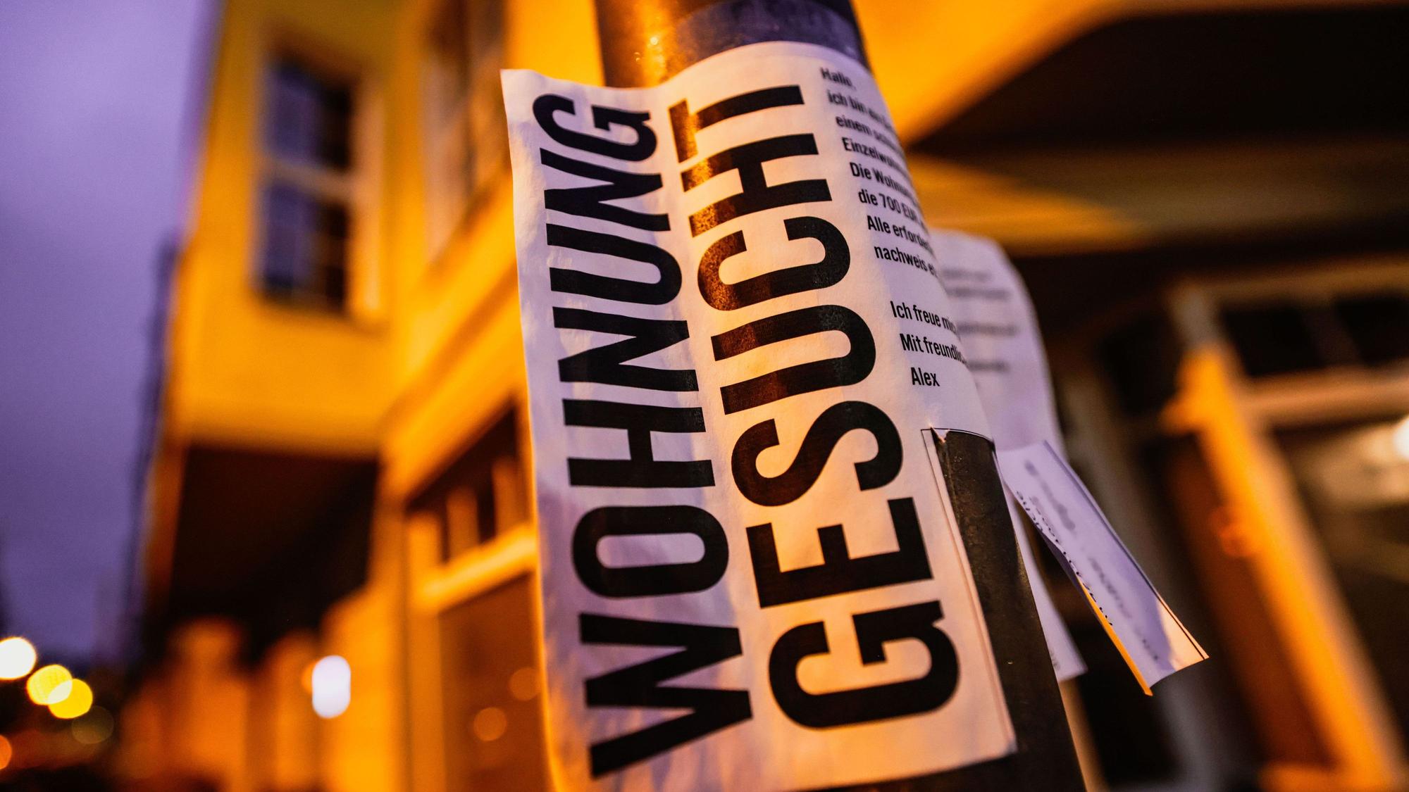 Ein Zettel mit der Aufschrift „Wohnung gesucht“ hängt vor Wohnhäusern in Köln. (Archivbild)