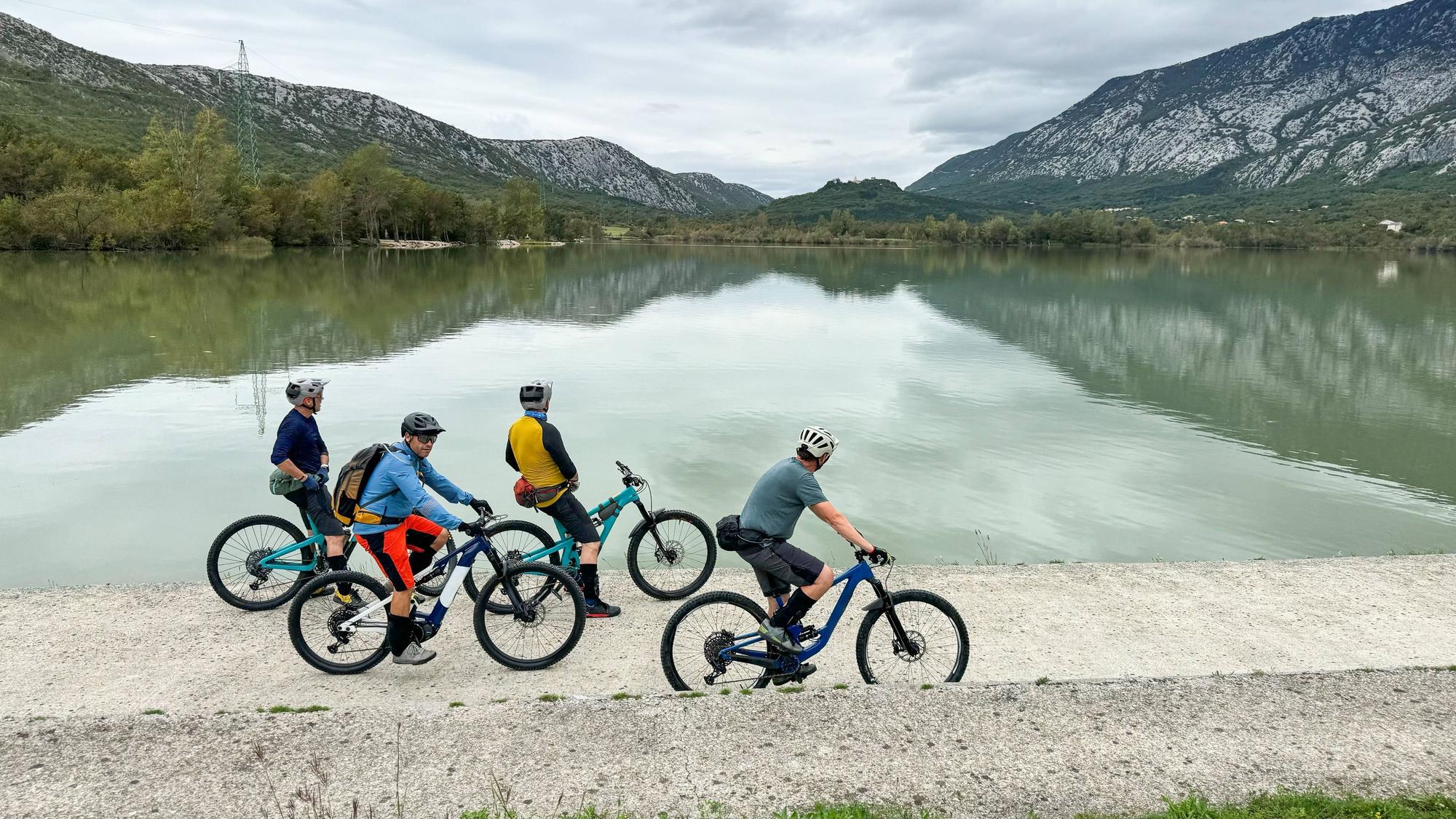 Gruppe Radfahrer mit E-Bikes am See vor Bergen