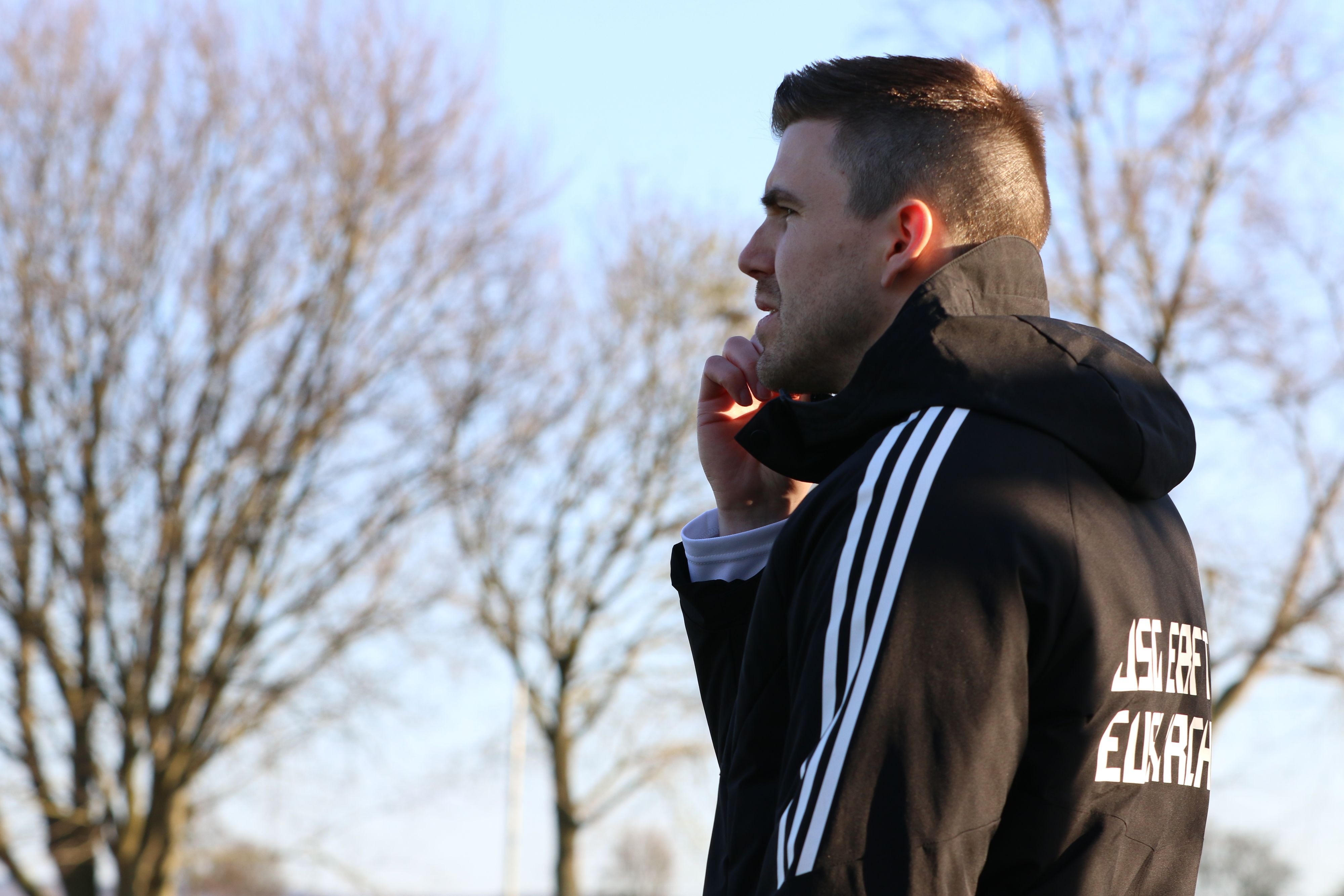 Marcel Schmitz trägt eine Winterjacke und greift sich mit einer Hand ans Gesicht.