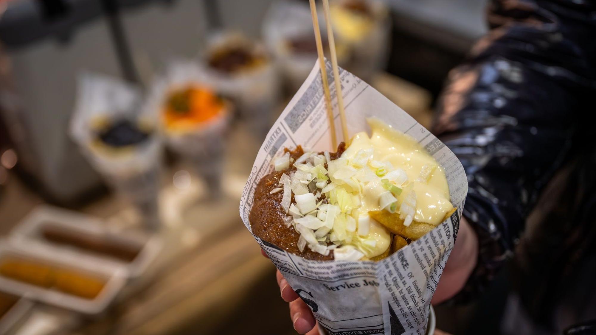 Eine Messebesucherin hält eine Tüte Pommes in der Hand