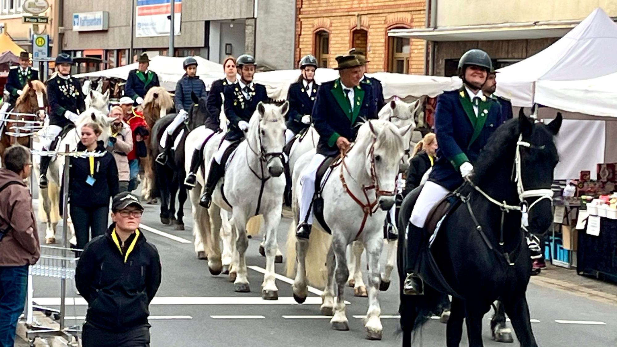 Auf einer Straße sind Reiter und Pilger zu Fuß zu sehen.