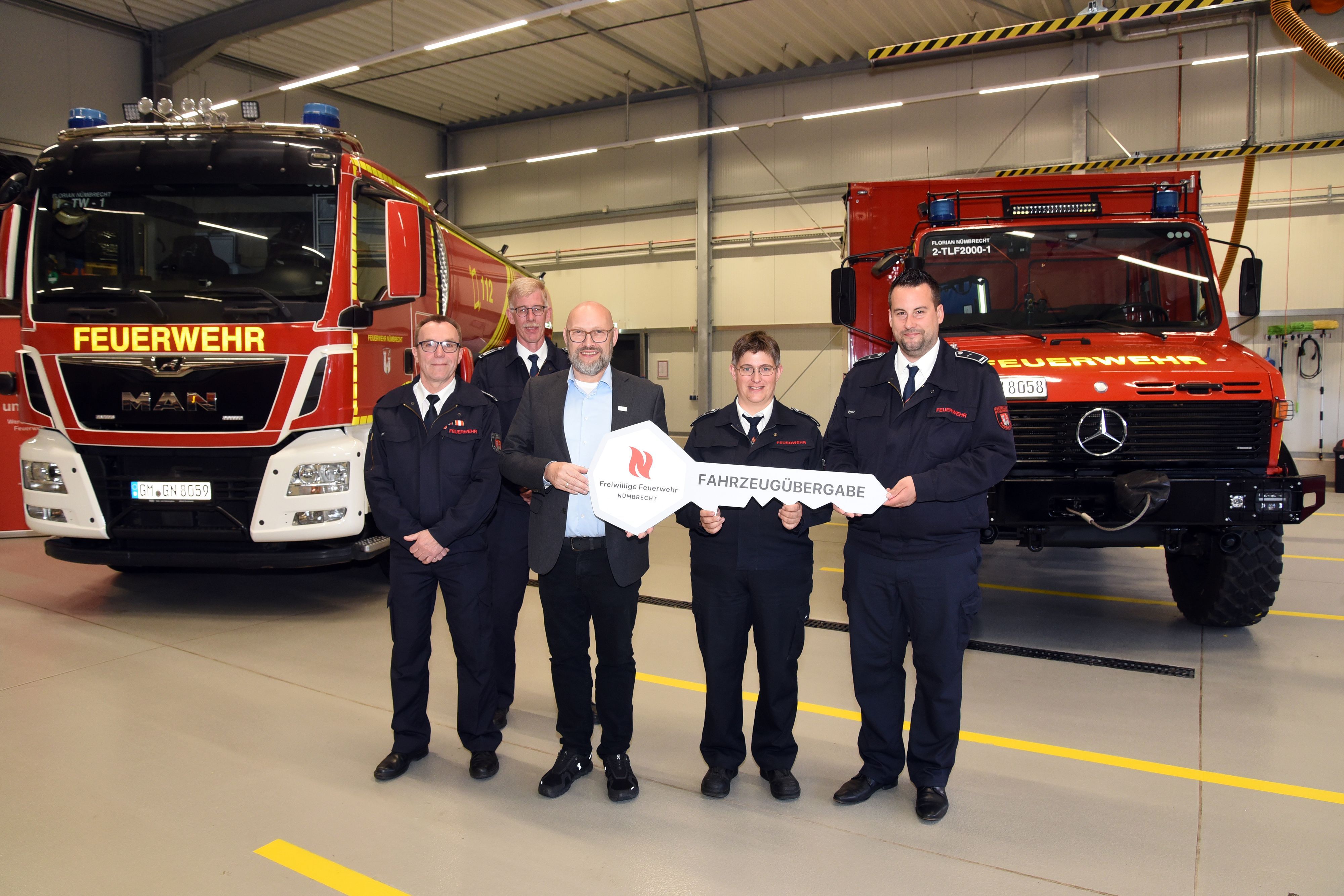 Zu sehen ist die symbolische Schlüsselübergabe für zwei neue und umgebaute Feuerwehr-Fahrzeuge an Vertreter der Freiwilligen Feuerwehr Nümbrecht.