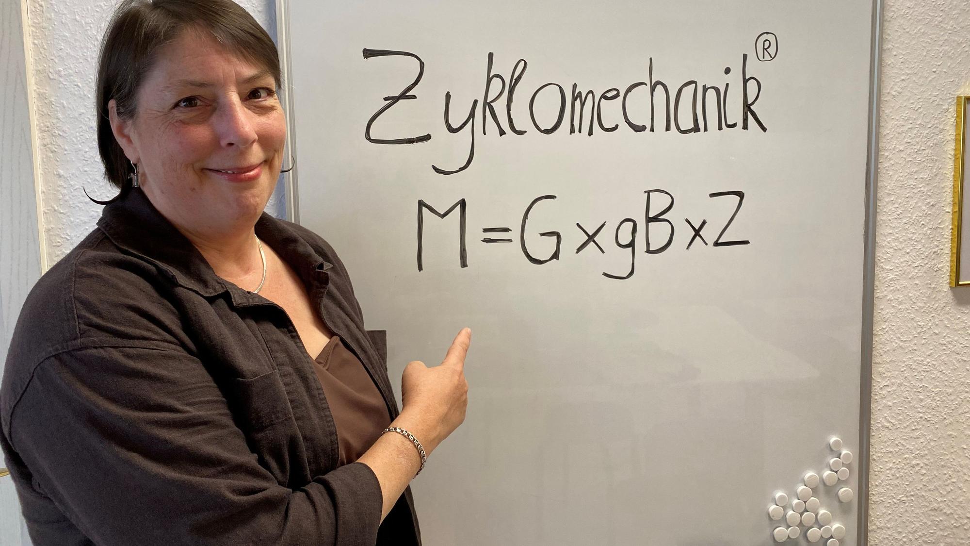 Eine Frau zeigt auf ein Plakat, auf dem steht Zyklomechanik