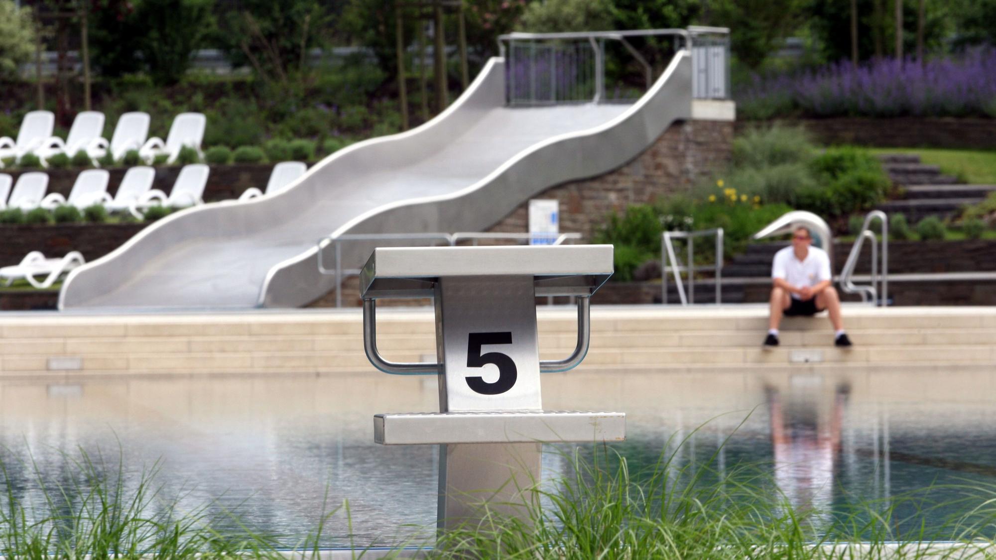Ein Schwimmmeister sitzt am Rand des noch leeren Nichtschwimmerbeckens in Rösrath-Hoffnungsthal.