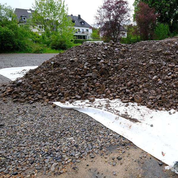 Erdaushub aus Olef und Urft wird auf dem Katharinenhof-Parkplatz in Gemünd auf einer weißen Plane zwischengelagert.