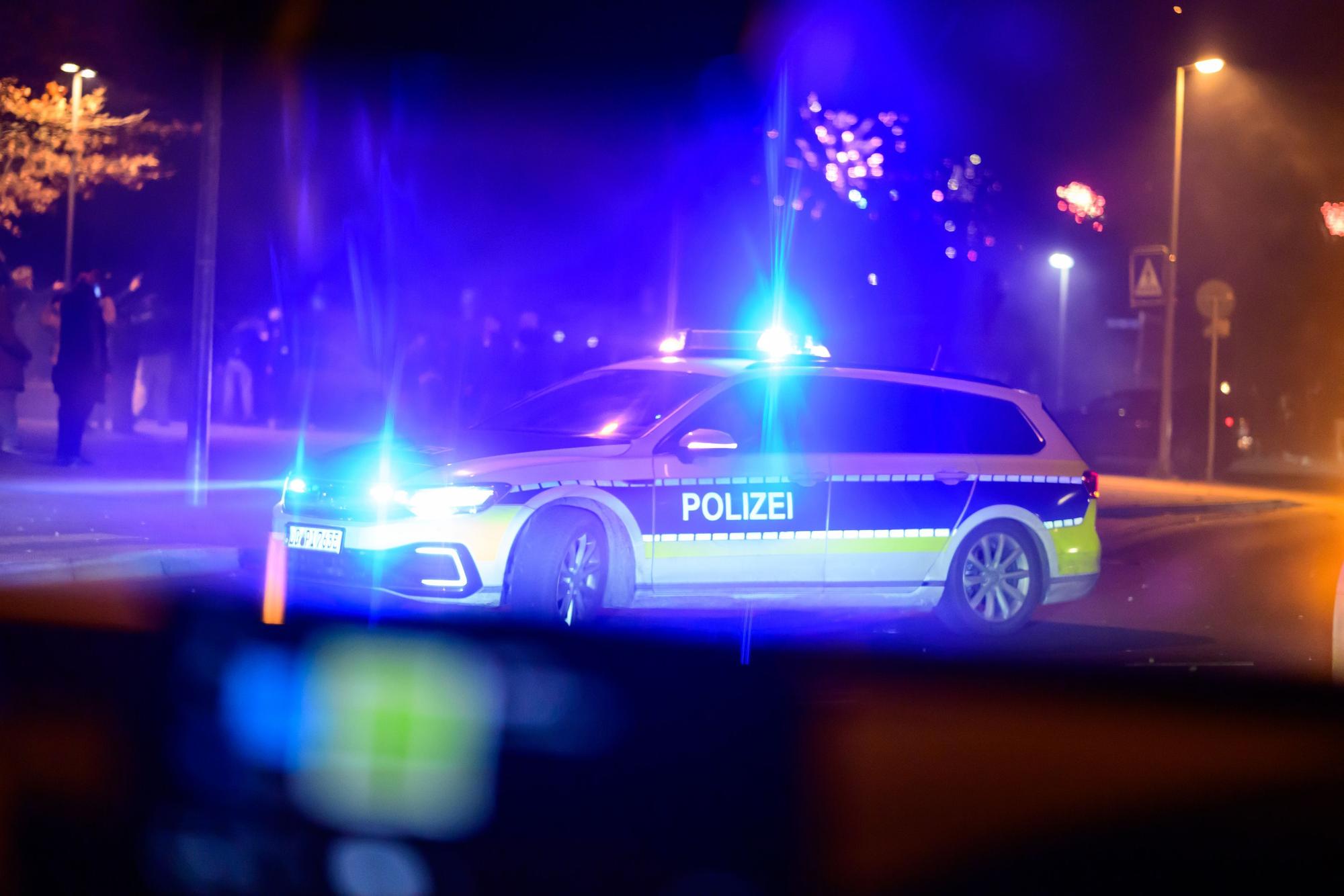 Ein Einsatzfahrzeug der Polizei steht nachts mit Blaulicht auf einer Straße.