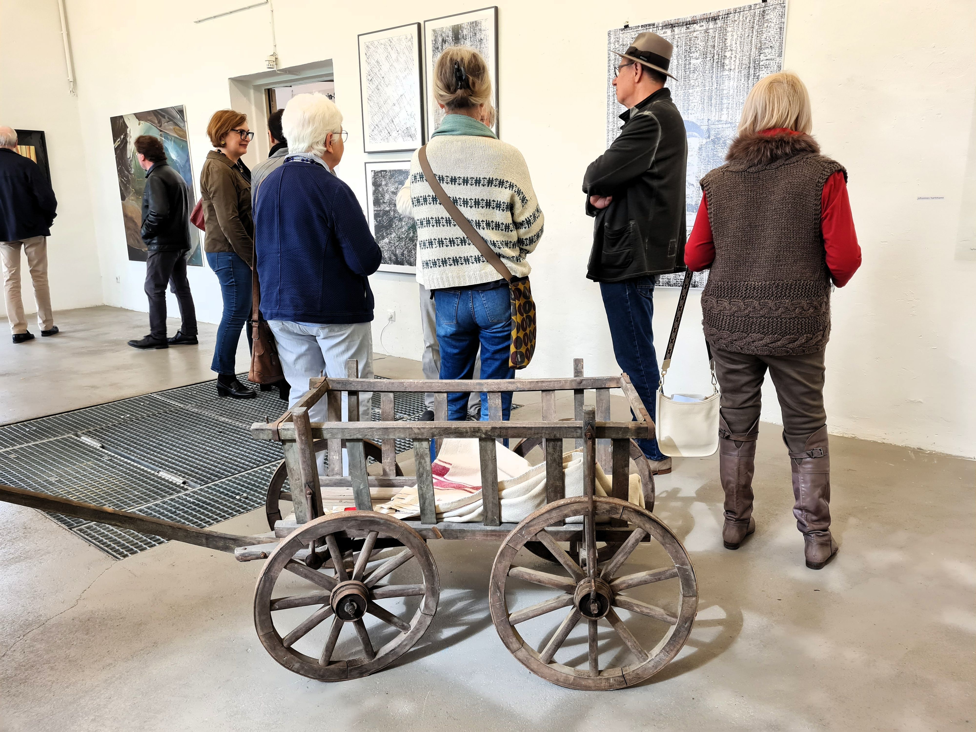 Menschen stehen im Ausstellungsraum des Pumpwerks in Siegburg und betrachten Gemälde.