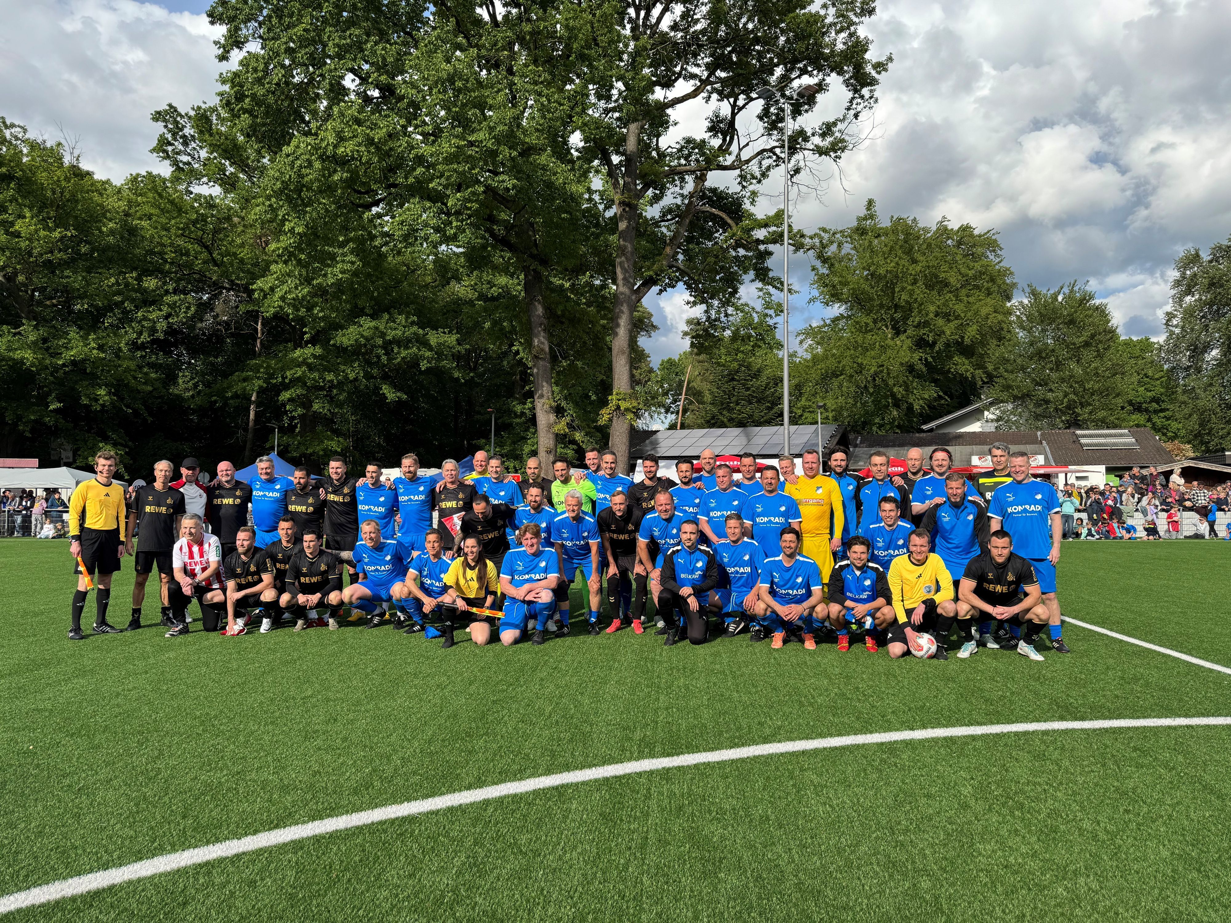 Gruppenbild von zwei Fußballteams in blauen und schwarzen Trikots