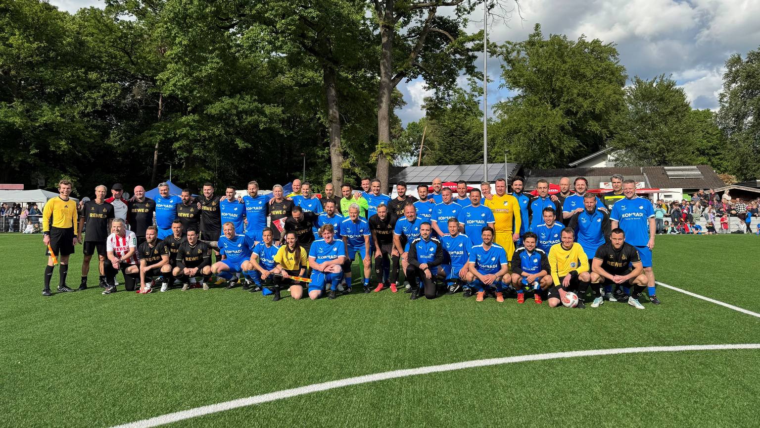 Gruppenbild von zwei Fußballteams in blauen und schwarzen Trikots
