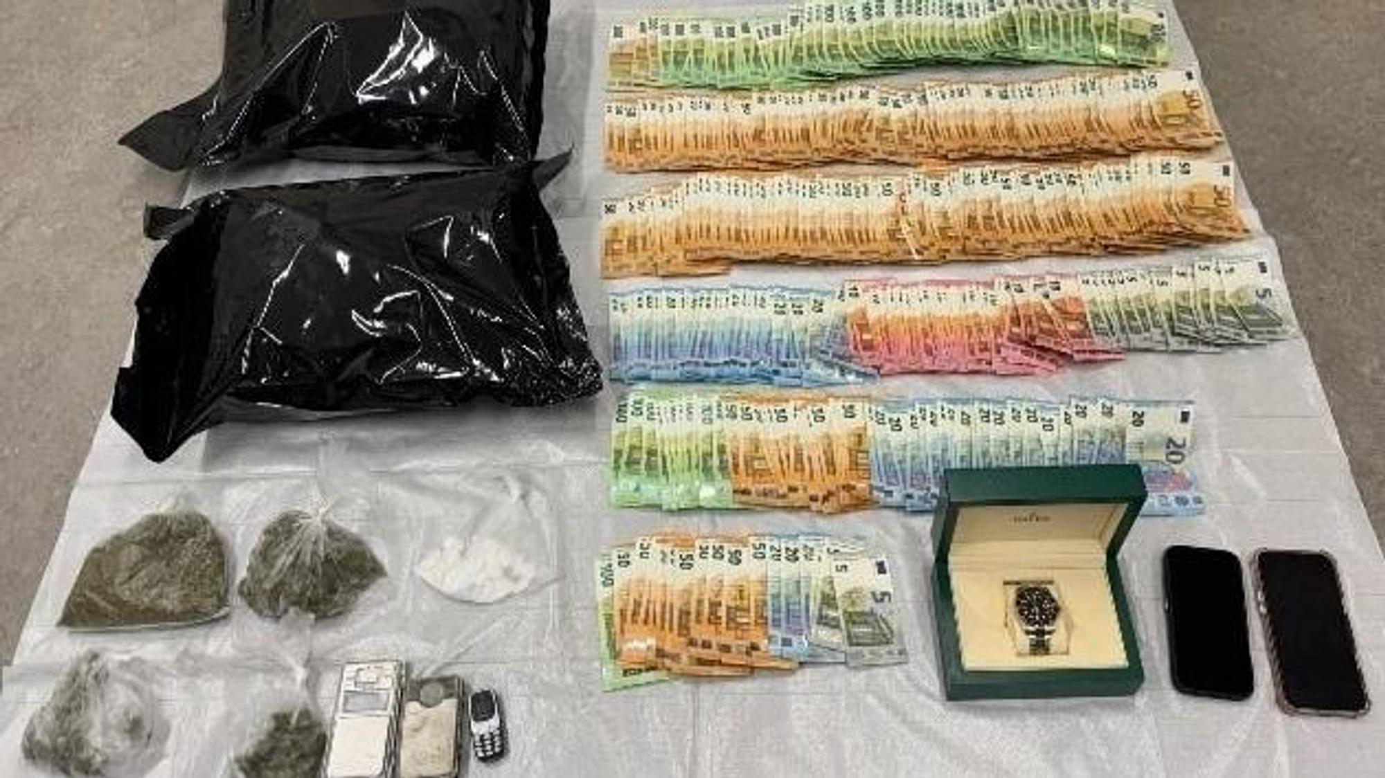 Sichergestellte Drogen, Bargeld und eine Rolex-Uhr auf einem Tisch.