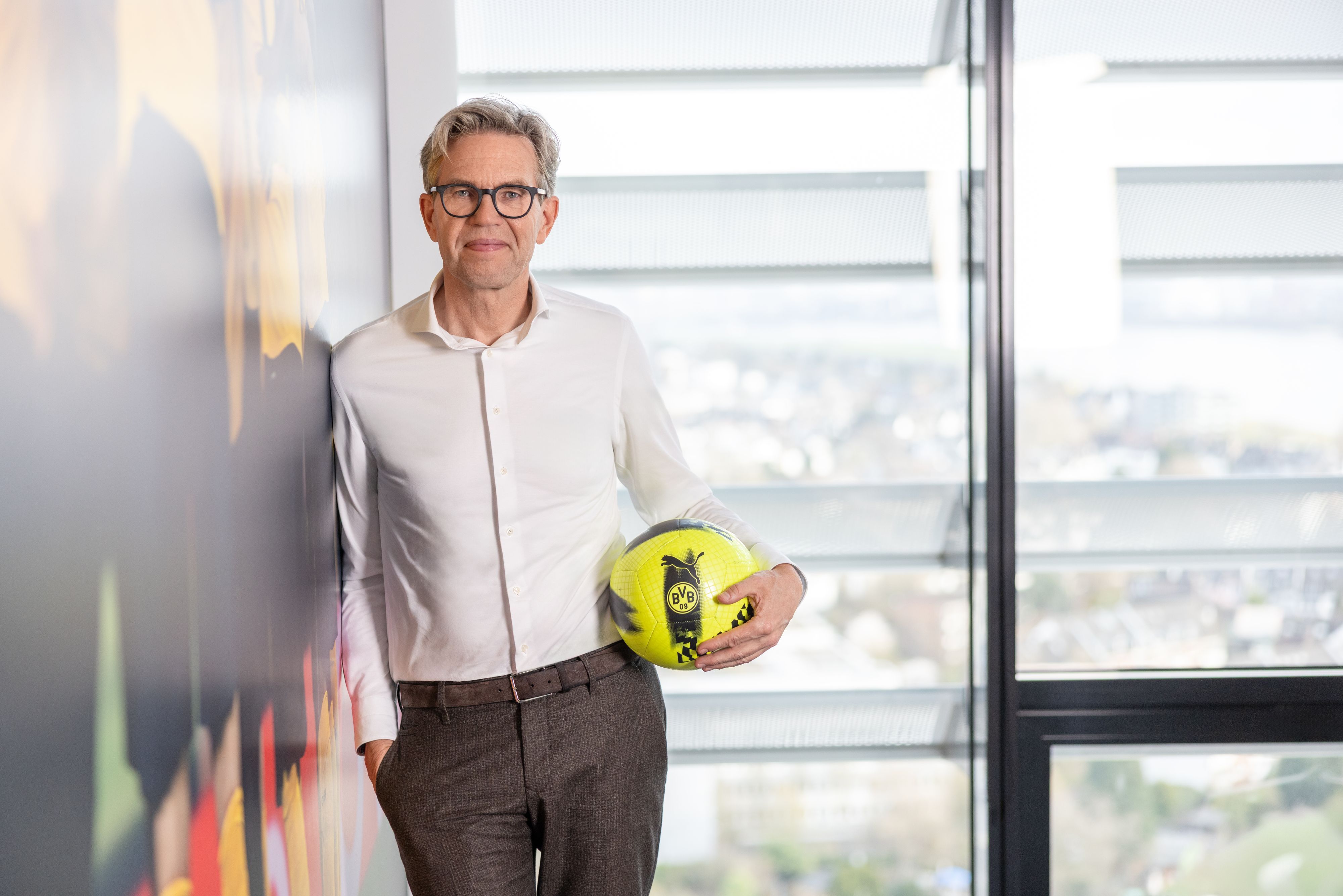 De Groot ist im Halbporträt zu sehen. Er hat eine BVB-Ball unterm Arm.