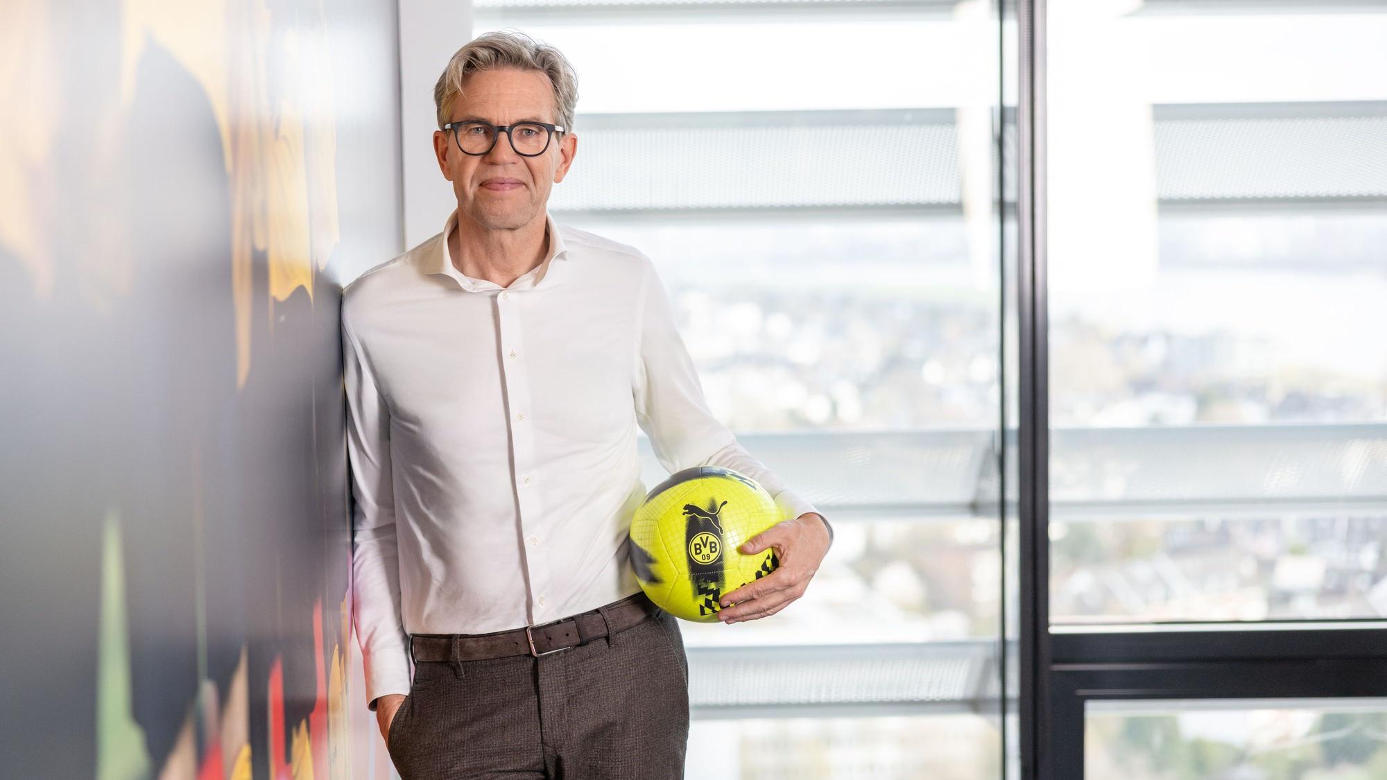 De Groot ist im Halbporträt zu sehen. Er hat eine BVB-Ball unterm Arm.