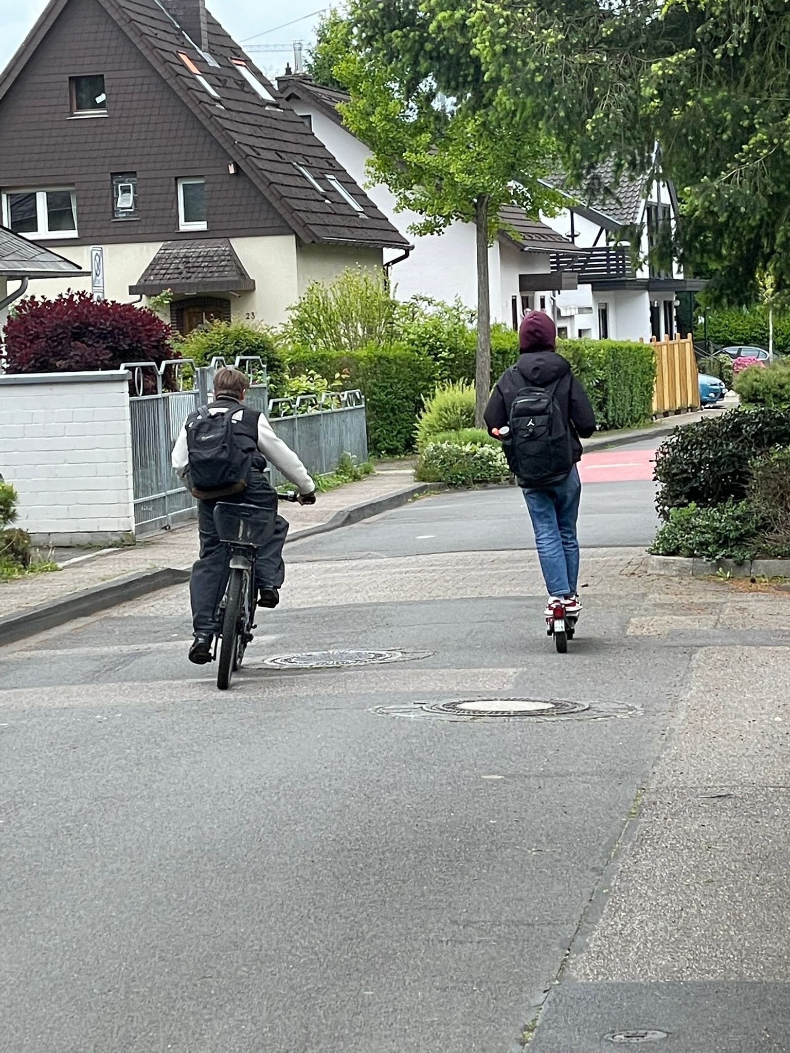Ein Junge faährt auf dem Farrad, ein Junge auf dem Roller.
