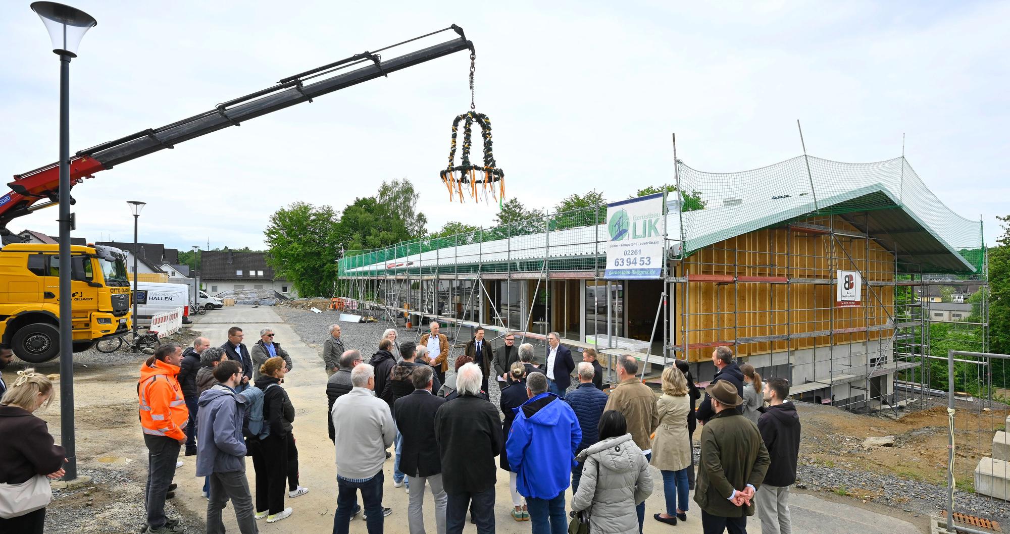 Zu sehen ist die neue Sporthalle, über der ein Richtkranz schwebt.
