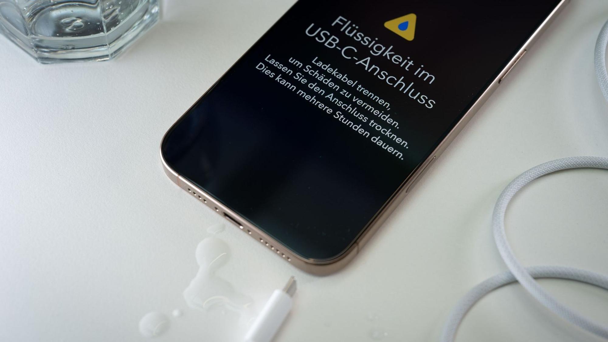 Ein iPhone mit einer Flüssigkeitswarnung und Wassertropfen