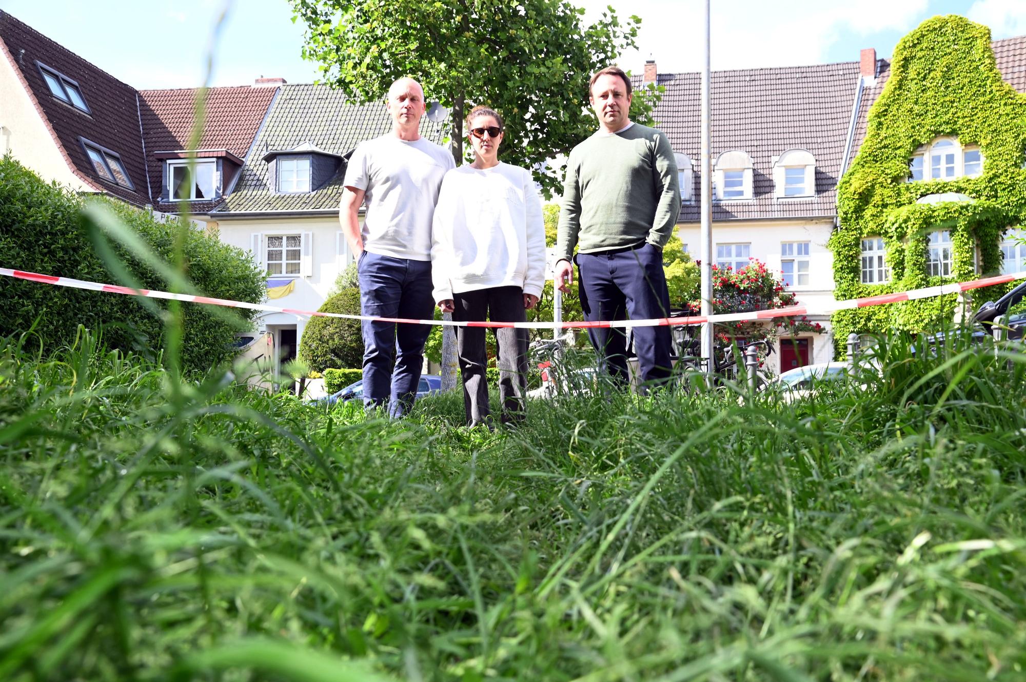 Zwei Männer und eine Frau stehen auf einer Grünfläche am Pauliplatz in Köln-Braunsfeld.