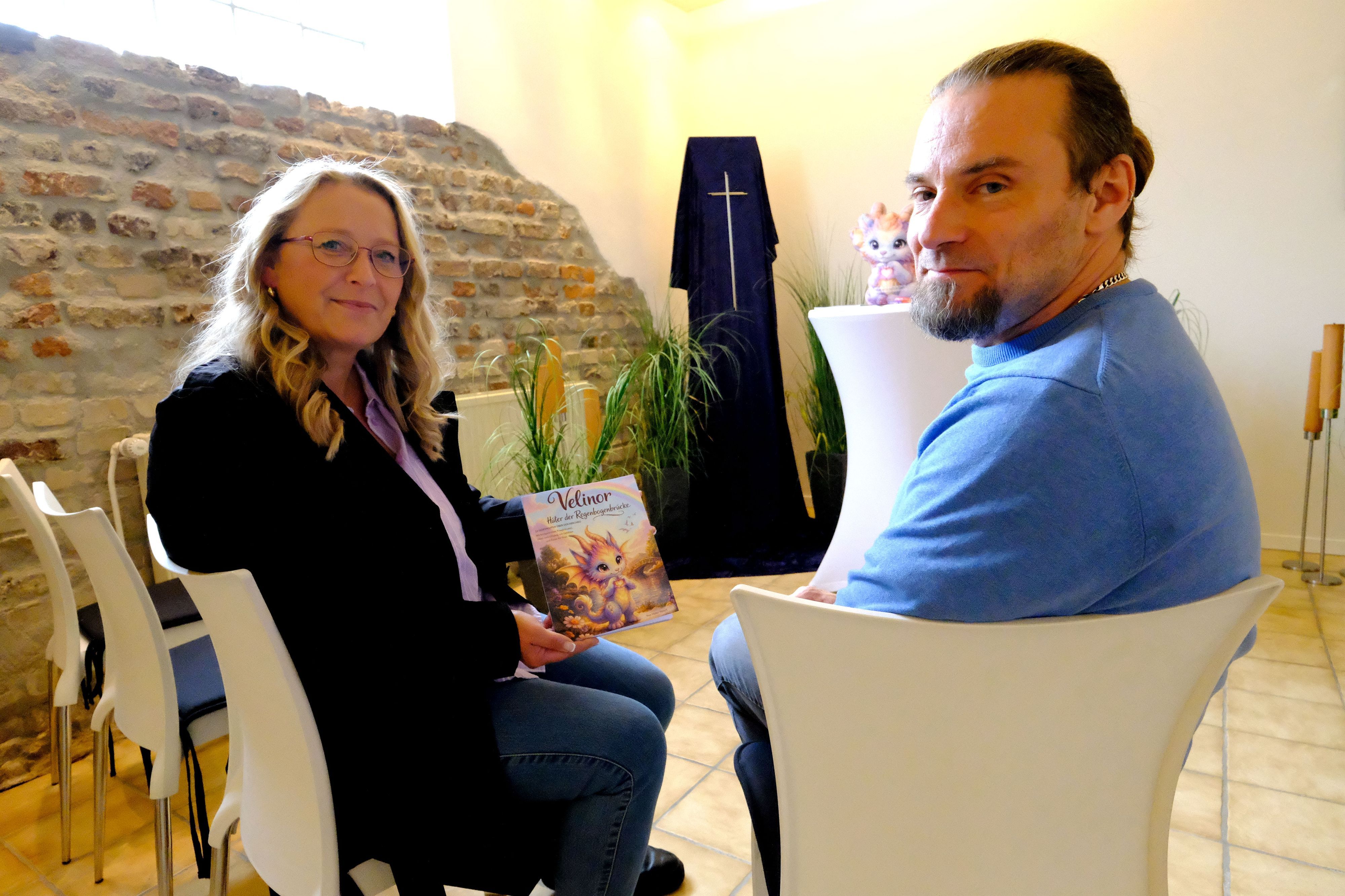 Die Trauerrednerin und Autorin Kaja Müller-Welsch mit Bestattermeister Marcel Ohles in der Trauerhalle des Mechernicher Bestattungshauses. Müller-Welsch hält ein Kinderbuch in der Hand.