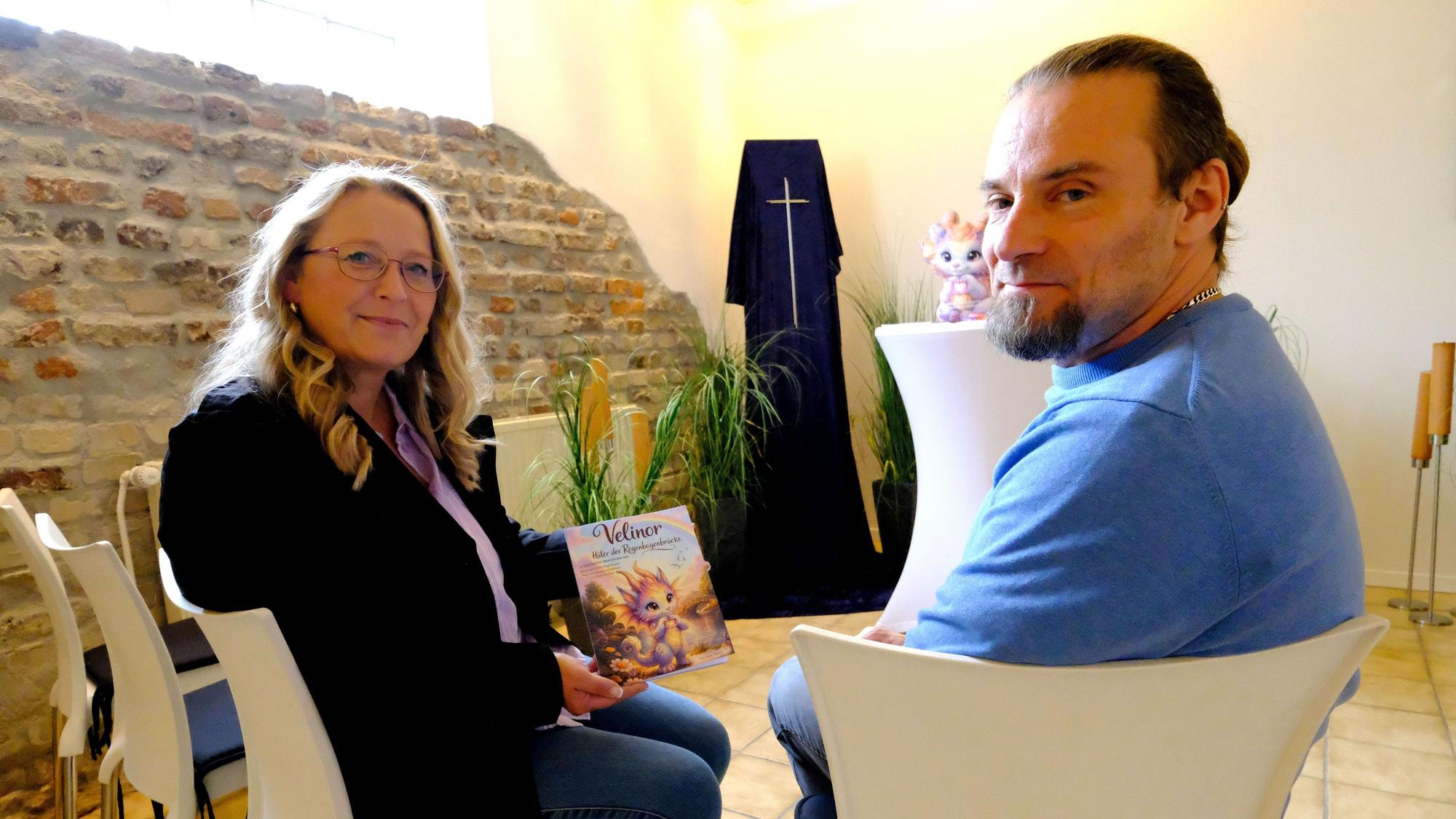 Die Trauerrednerin und Autorin Kaja Müller-Welsch mit Bestattermeister Marcel Ohles in der Trauerhalle des Mechernicher Bestattungshauses. Müller-Welsch hält ein Kinderbuch in der Hand.