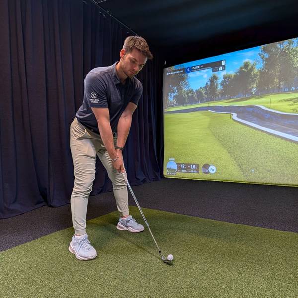 Das Foto zeigt den Inhaber mit Golfschläger am Abschlag vor der Videowand.
