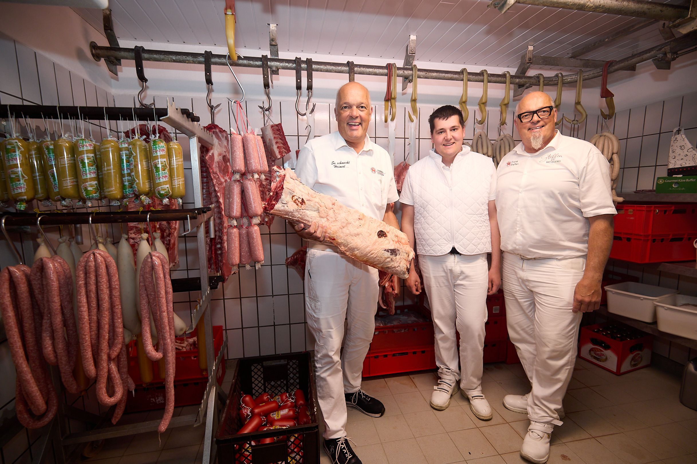 Drei Männer in weißer Kleidung stehen in den Produktionsräumen der Metzgerei Steffen in Gemünd.