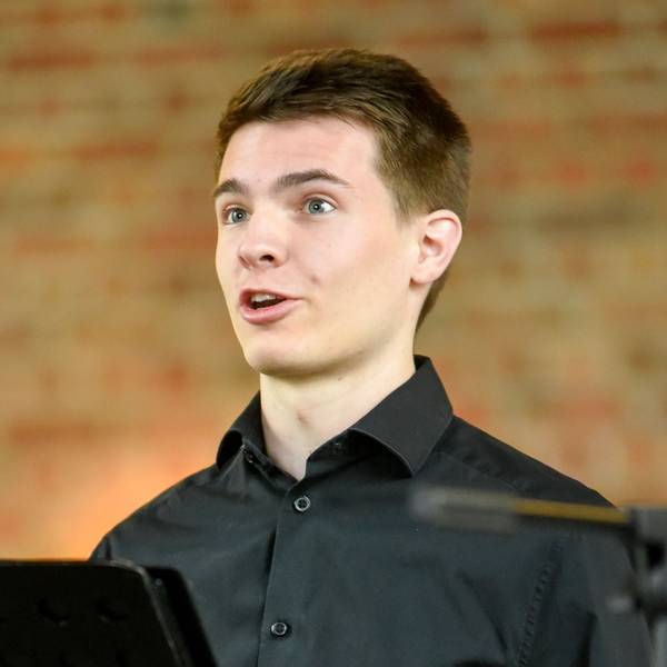 Auf dem Bild ist ein junger Mann zu sehen, der singt.